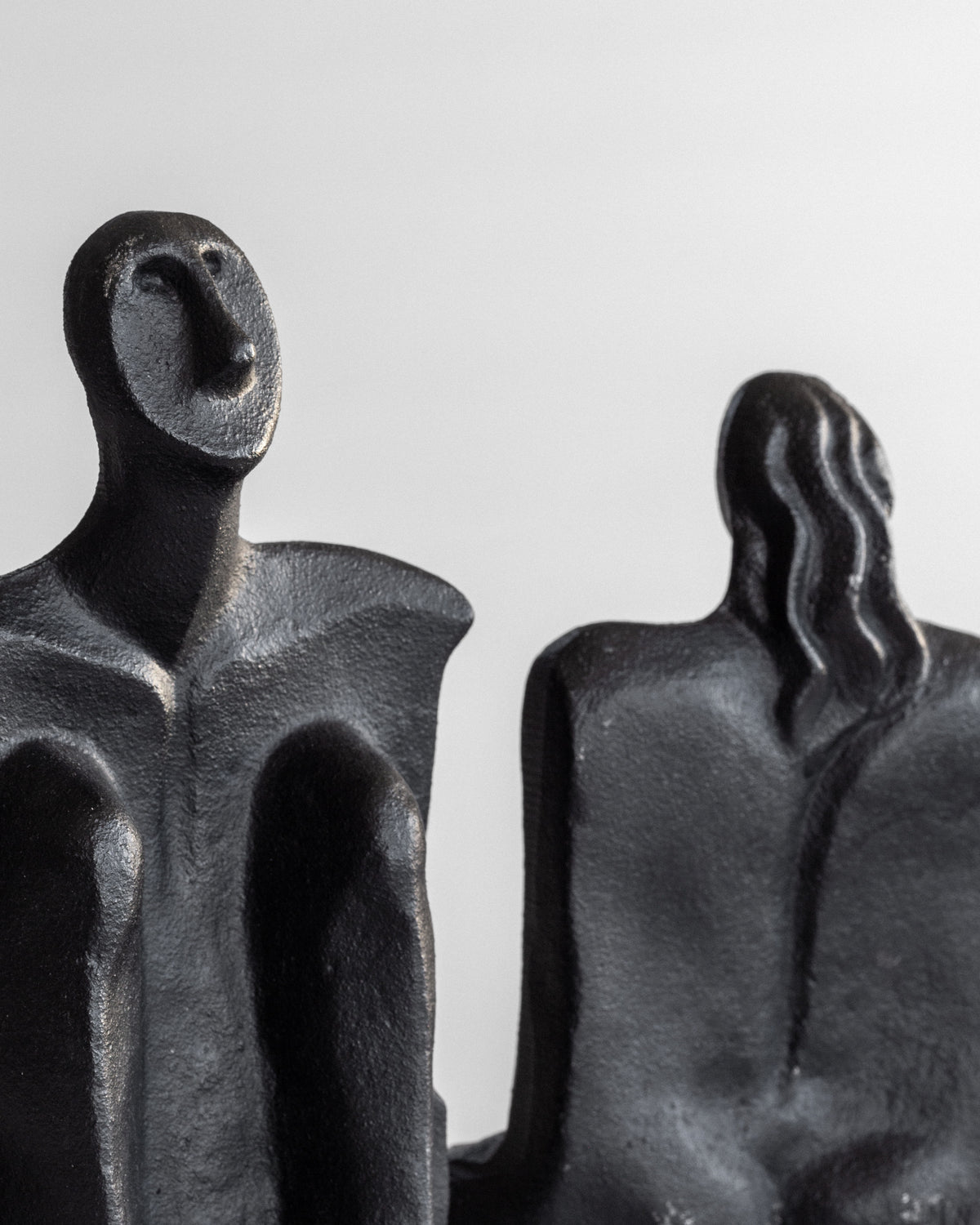 The "Male and Female Sculptures" by Marita Norin for Spigel are abstract black cast-iron figures with one featuring a smooth face and the other a wavy back, resembling elegant bookends, set on a plain light background.
