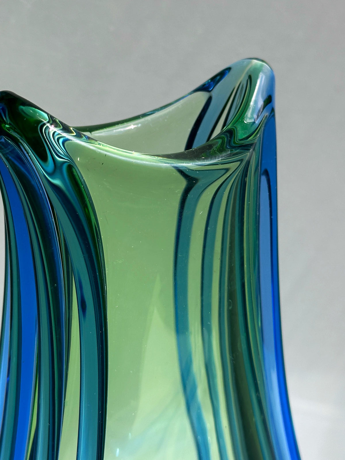 Close-up detail of blue-green Bohemian glass vase flowing curves