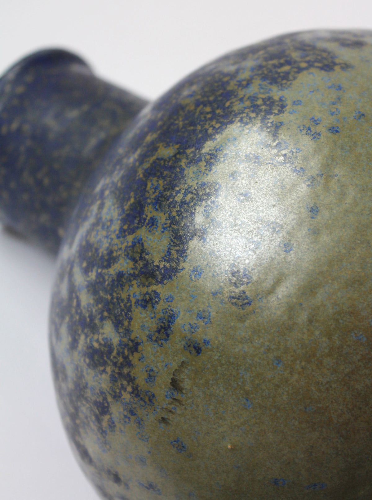 Close-up detail of speckled blue-gold ceramic jug surface texture