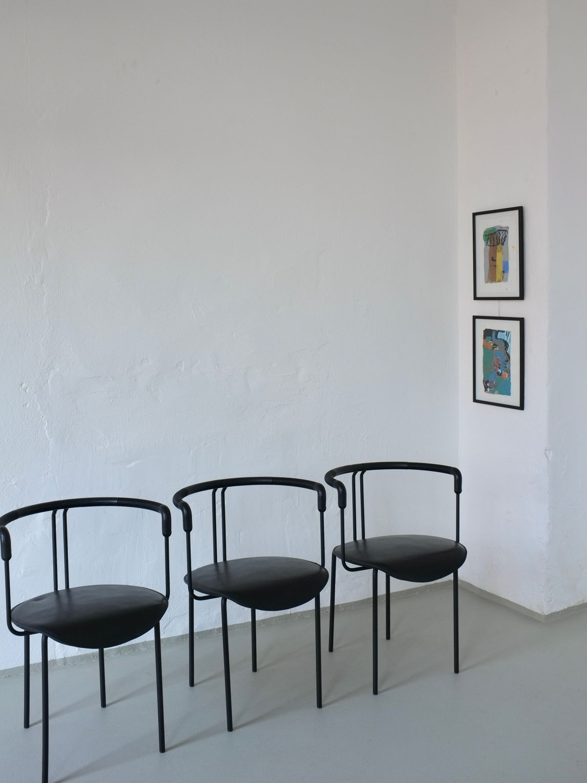 Three black leather postmodern armchairs arranged in minimalist room