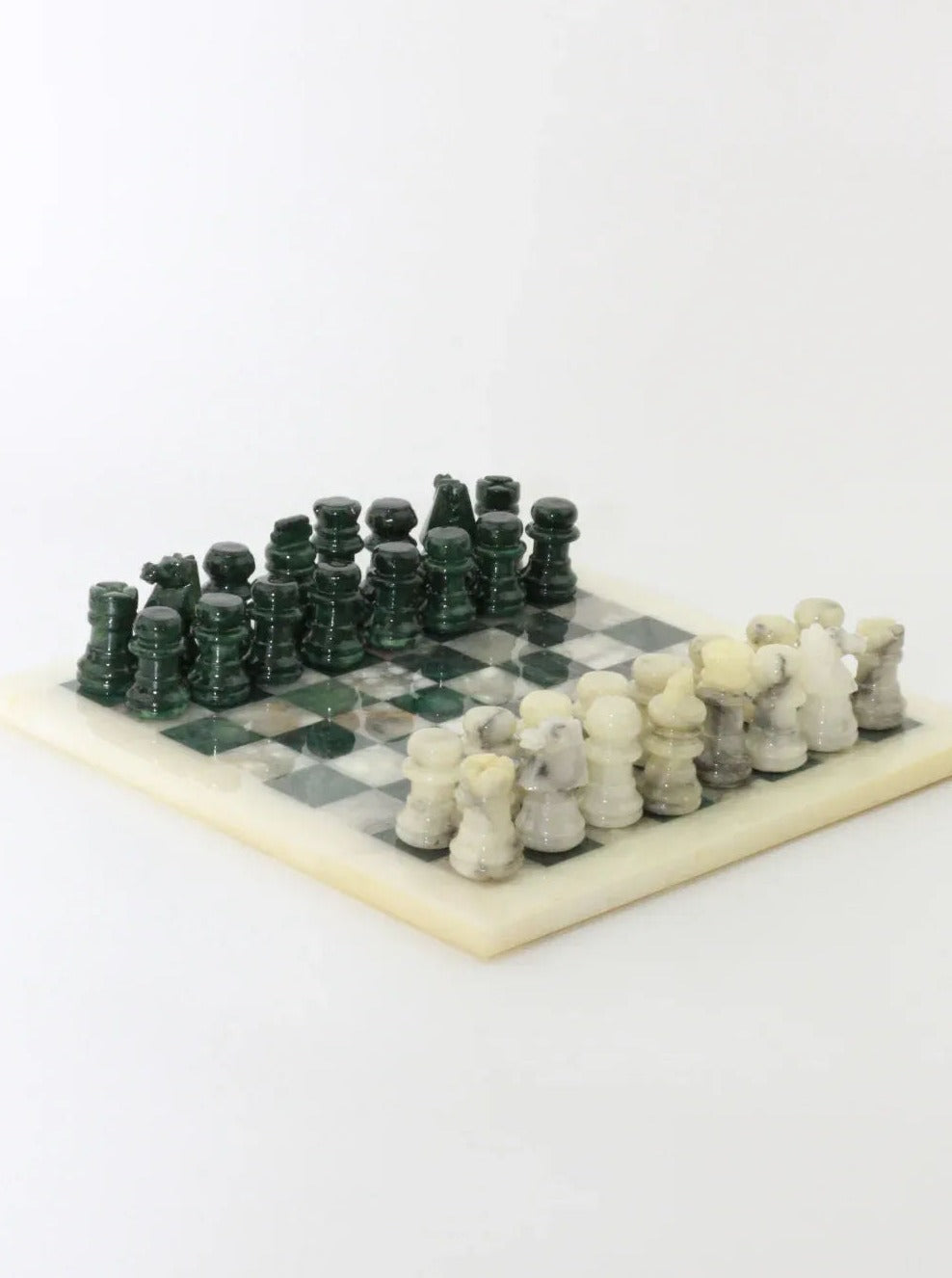 A Vintage Green and White Marble Chessboard by Boga Avante Shop displayed on a white surface. The vintage chessboard features alternating green and white squares, with elegant green and white marble pieces arranged for a game. The pawns, bishops, knights, rooks, queens, and kings are all distinguishable and neatly set up.