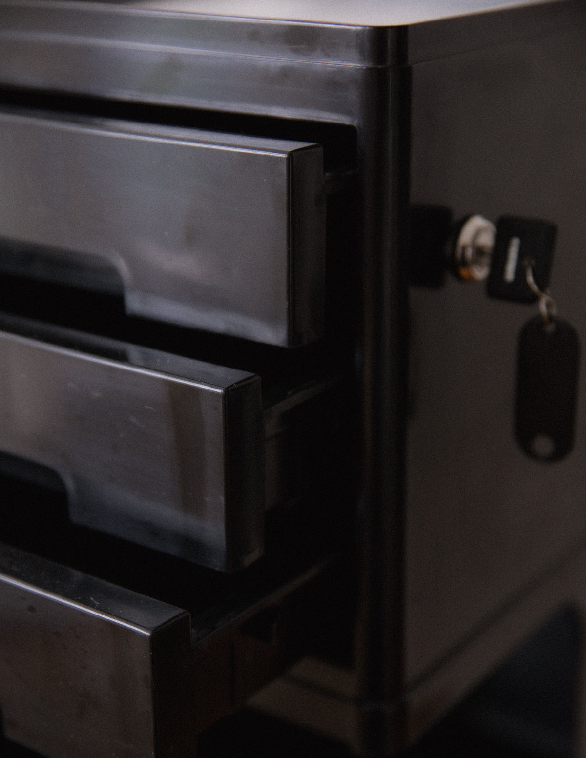 Dark grey storage trolley with multiple sliding drawers and side door detail
