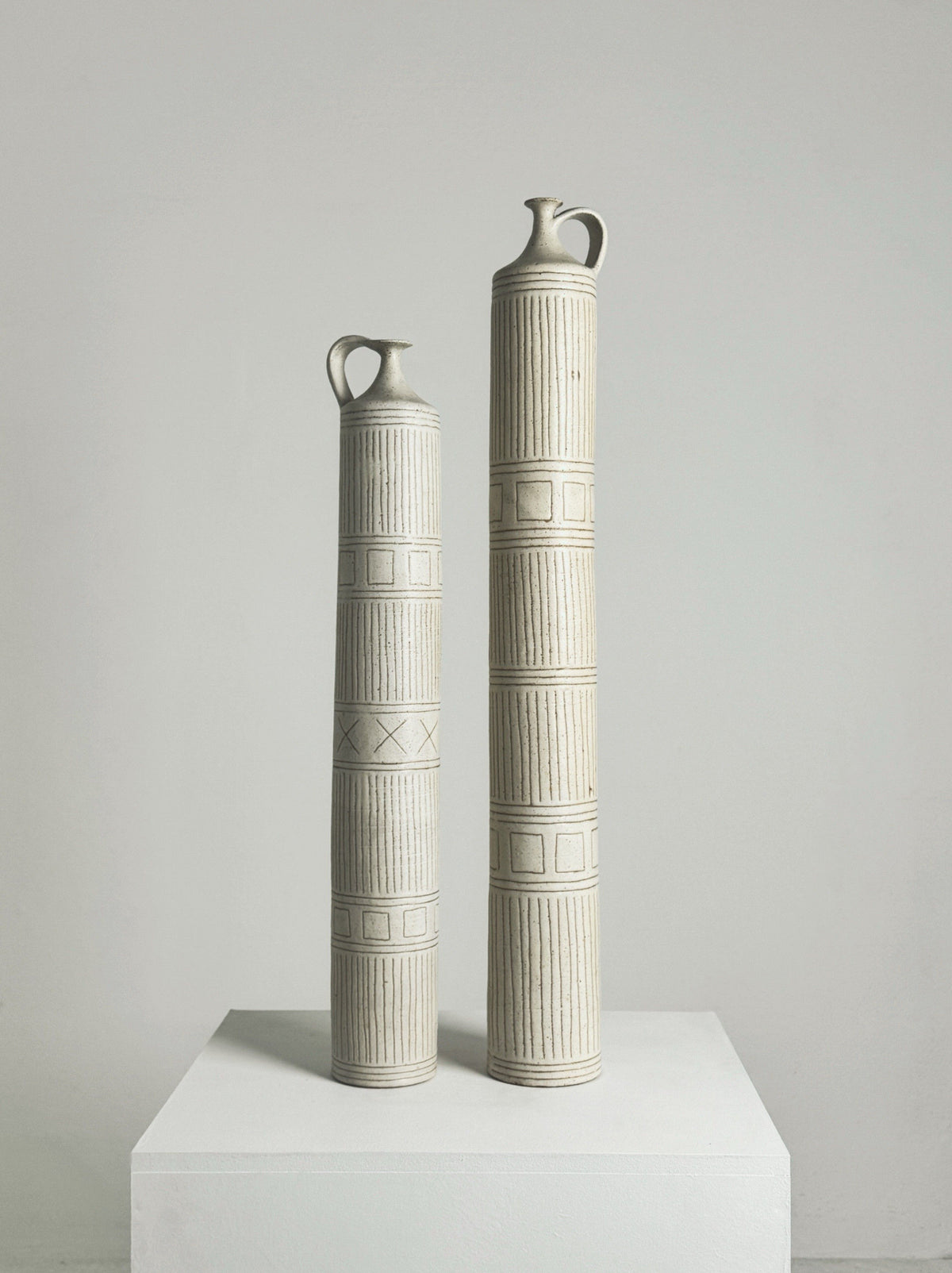 Two tall ceramic column bottles by Bruno Gambone with geometric patterns