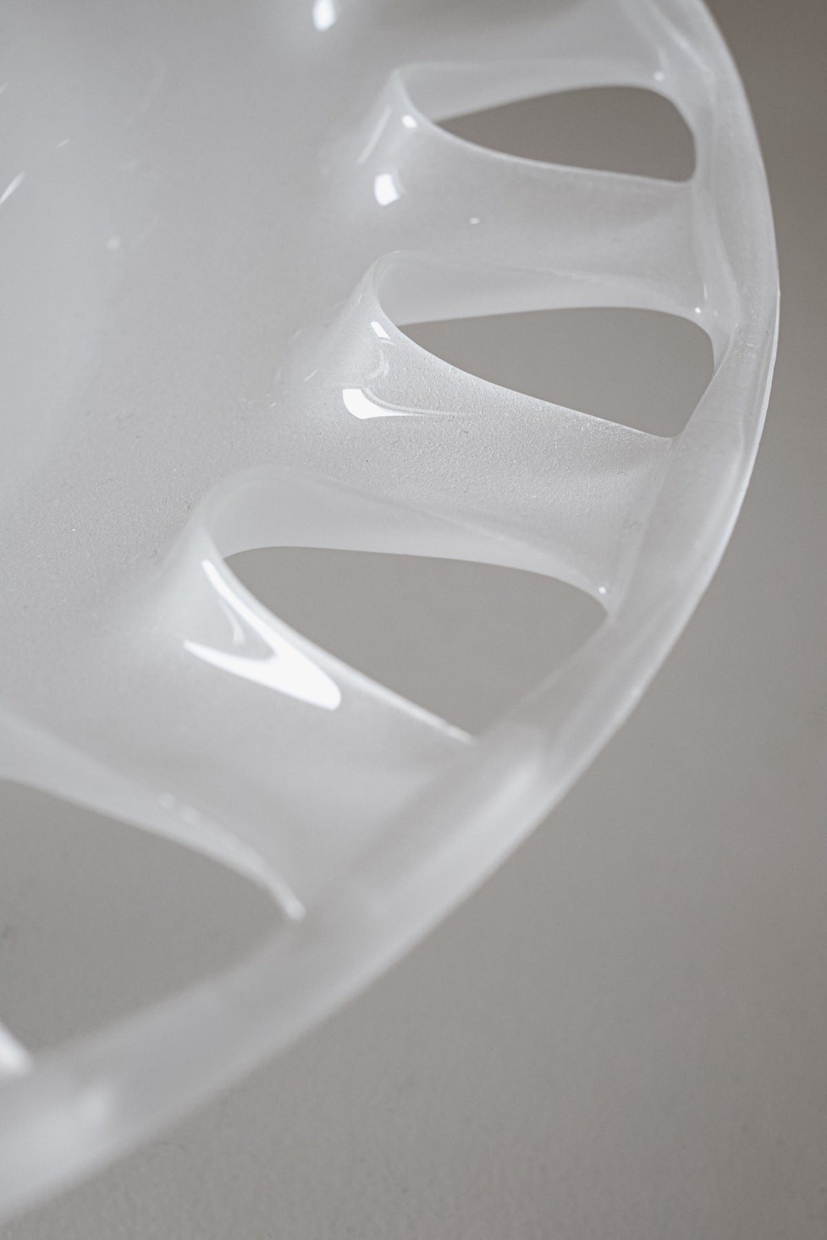 The "Large Bowl of Milk Glass" by septembre studios is featured against a plain gray background, highlighting its translucent white appearance with an intricate scalloped edge that showcases its glossy and smooth texture.