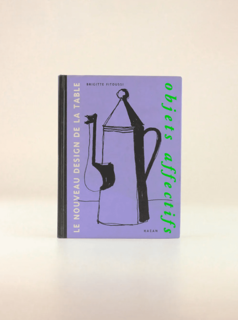 A book titled "Objets Affectifs: Le Nouveau Design de la Table" by Brigitte Fitoussi. The hardcover features a purple cover with a minimalist black drawing of a French press coffee maker and cup, showcasing an elegant blend of diseño moderno. The spine and author's name are visible. Available at Boga Avante Shop.