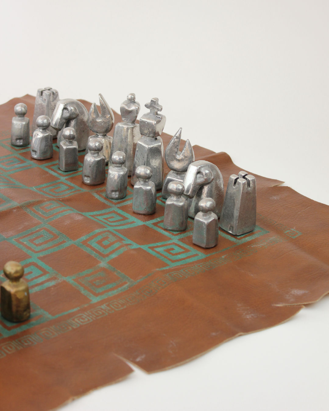 Close-up view of brutalist pewter chess pieces on leather board