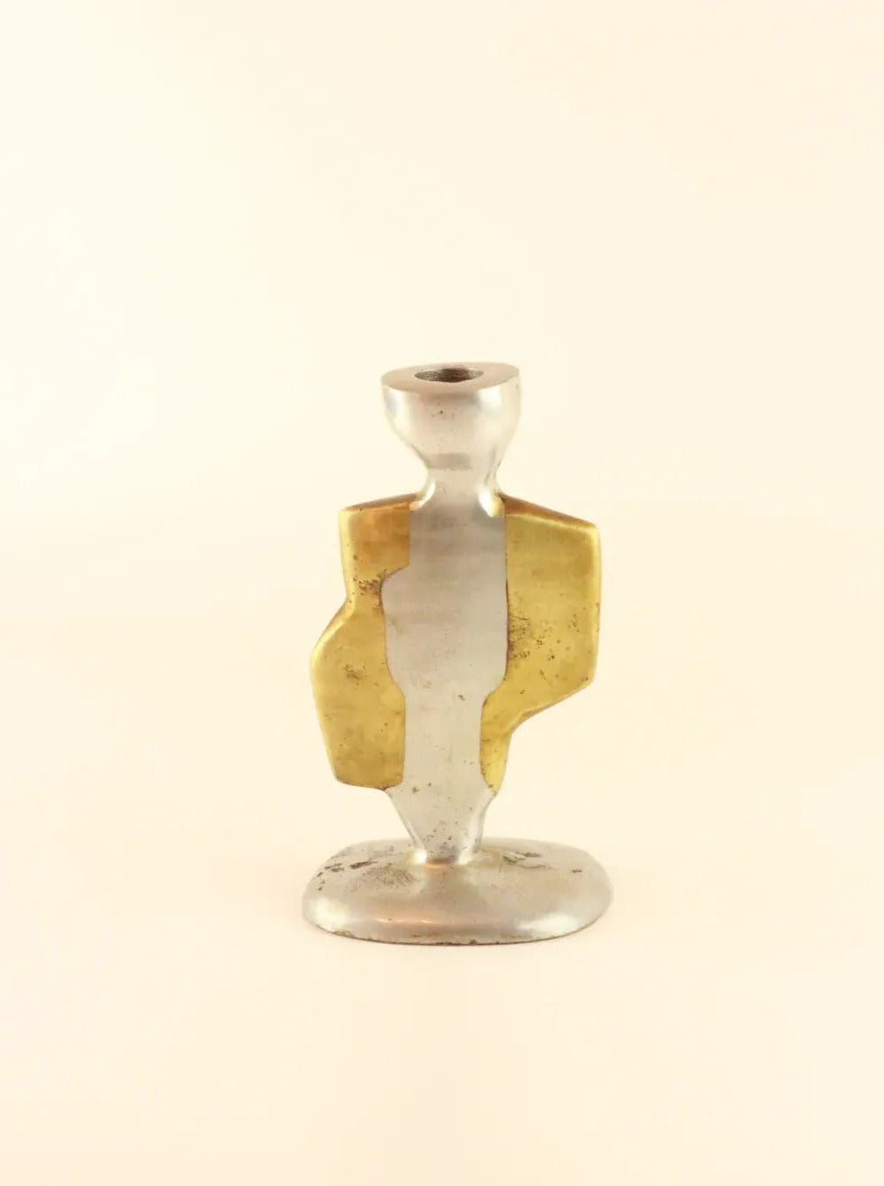 A vintage Brutalist Candleholders by Boga Avante Shop, possibly inspired by David Marshall's artistry, featuring a simplistic, abstract human figure design. The candleholders combine aluminum and brass tones, with brass accents creating an overlay on part of the aluminum body. The background is plain and light-colored.