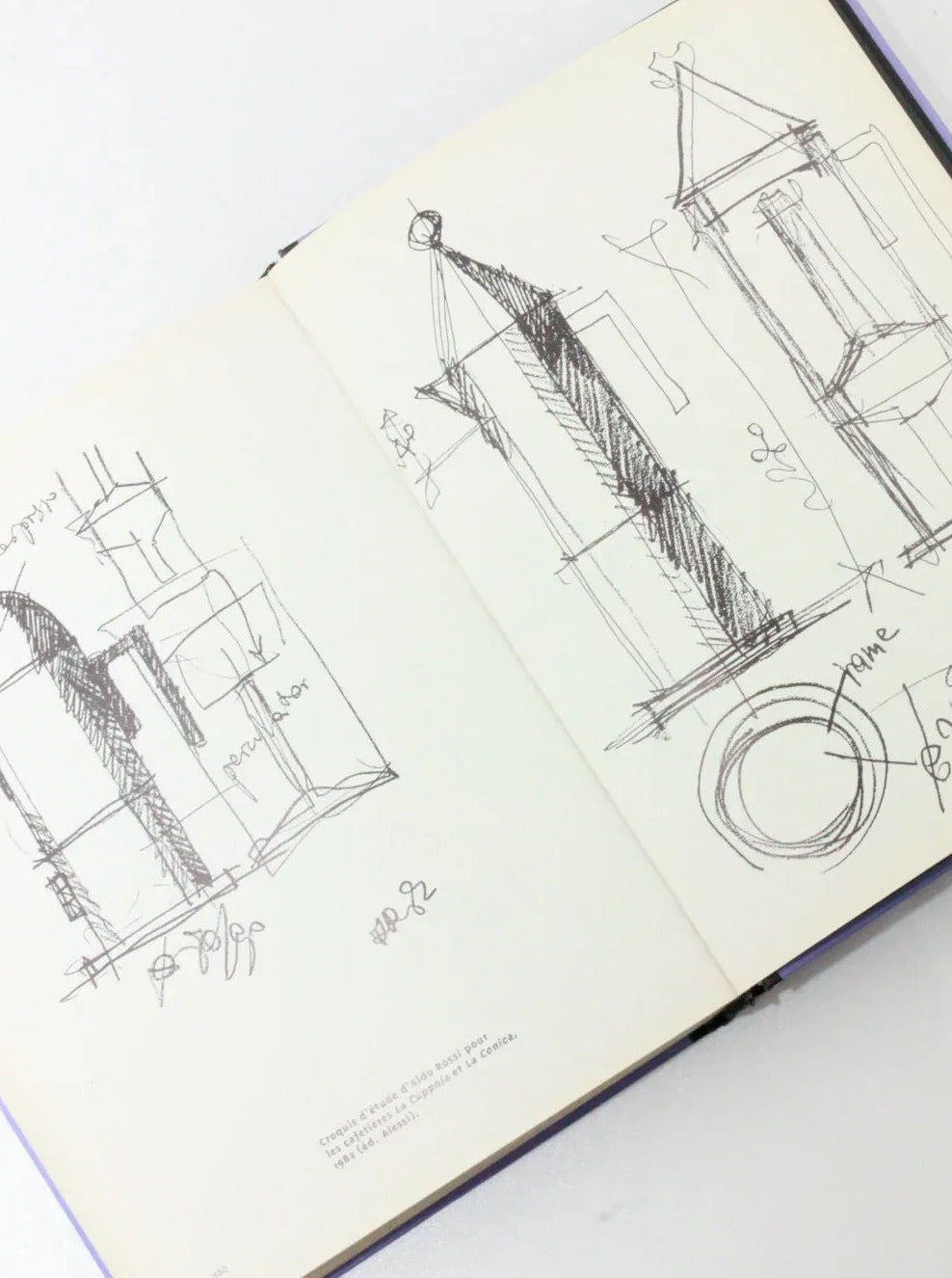 An open sketchbook with architectural drawings made in black ink. The left page shows rough sketches of buildings and measurements, while the right features structures, including a triangular roof and a cylindrical shape with additional notes and scribbles. Its Objets Affectifs: Le Nouveau Design de la Table by Boga Avante Shop exudes elegance in every detail.