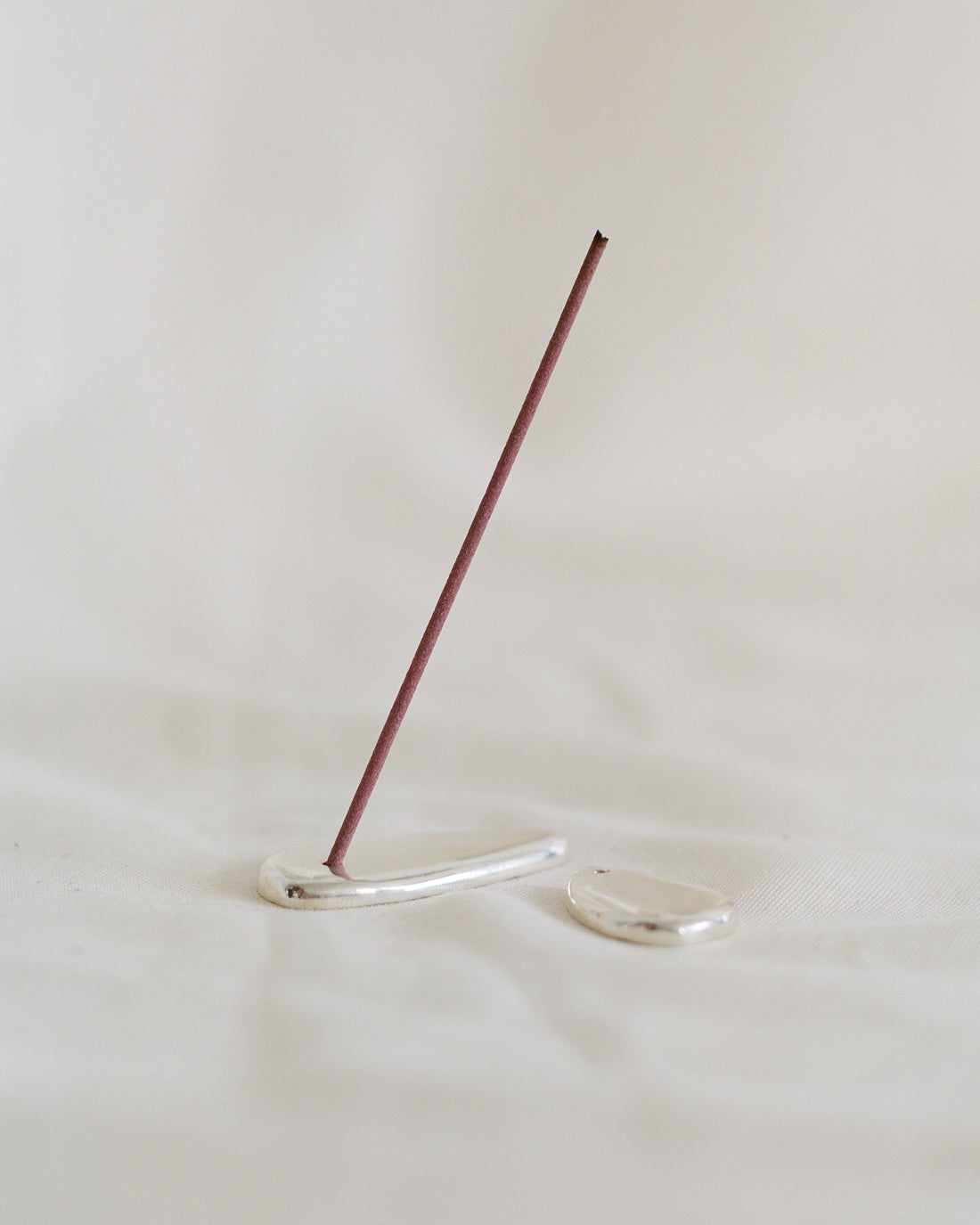 Clear glass incense holder with burgundy incense stick standing
