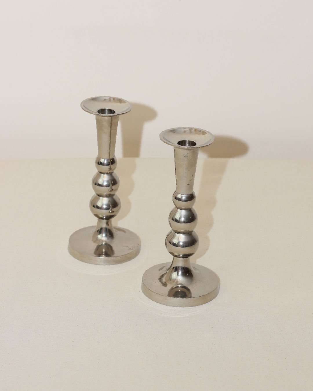 Two polished silver Acero candleholders with bulbous stems
