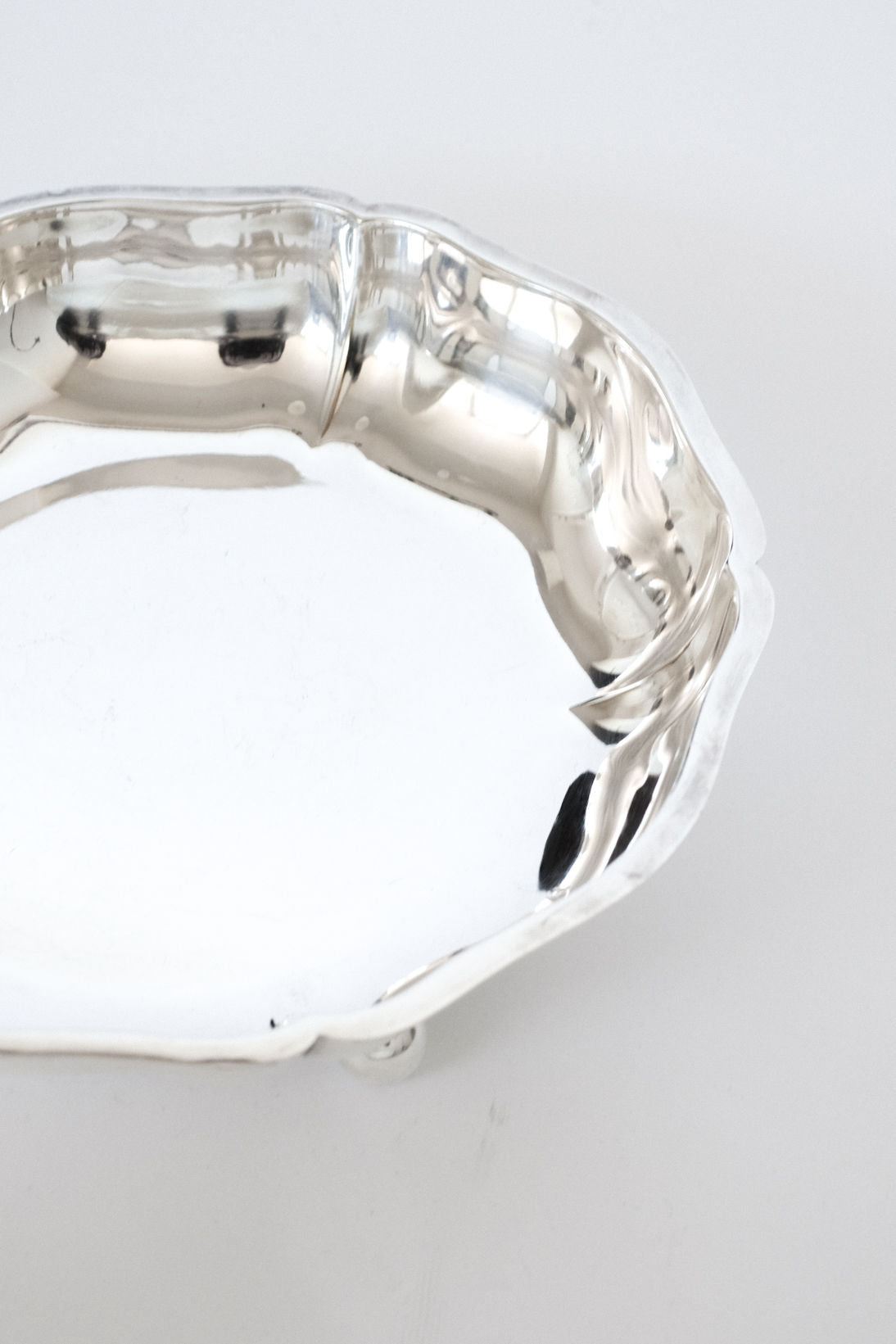 A close-up of the septembre studios Silver-plated Bowl showcases its shiny, scalloped edge and reflective surface against a light background, emphasizing the decorative rim.