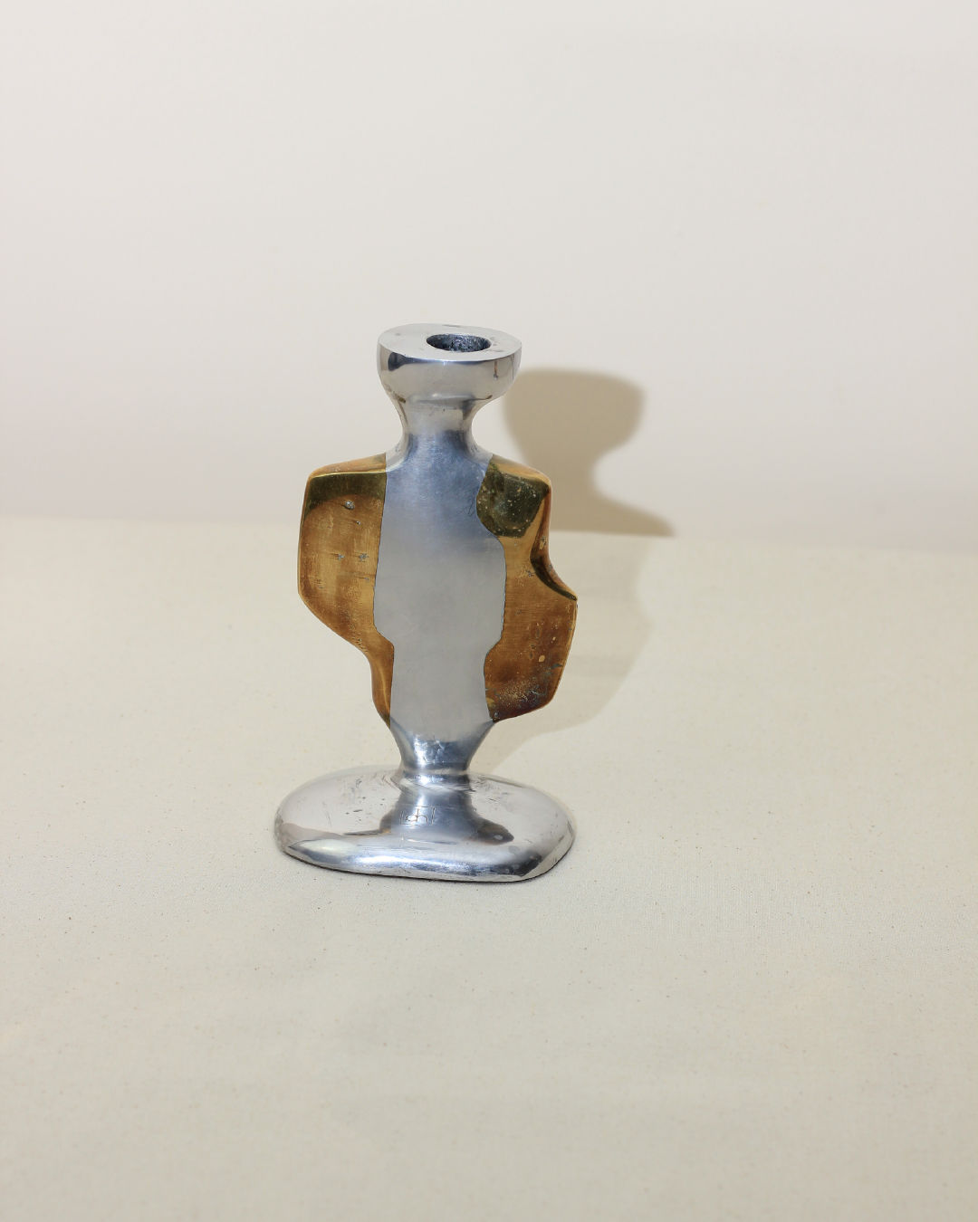 The Pair of Brutalist Candleholders by Boga Avante Shop features a modern, abstract design in aluminum and brass with silver and gold tones, smooth curved lines, and an asymmetrical shape reminiscent of vintage brutalist pieces.