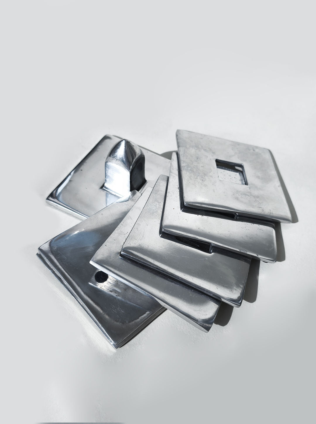 Stacked silver metal coasters showing geometric square design