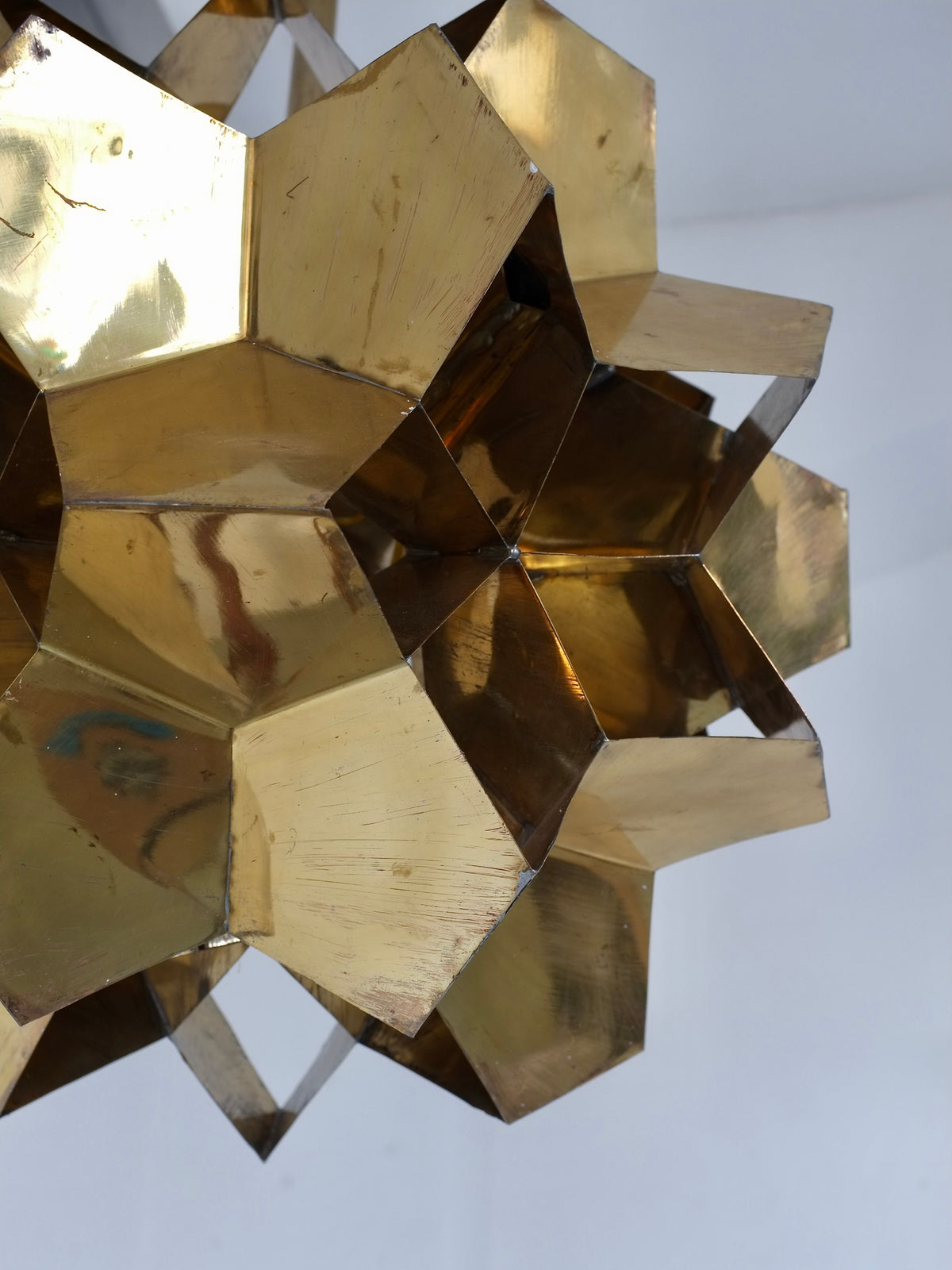 Close-up of the Brutalist Brass Chandelier by Veter Vintage, Latvia 70s—a sculptural, gold-toned geometric lampshade with polygonal facets that reflect light beautifully. Compatible with E27 bulbs and perfect against a light gray backdrop.