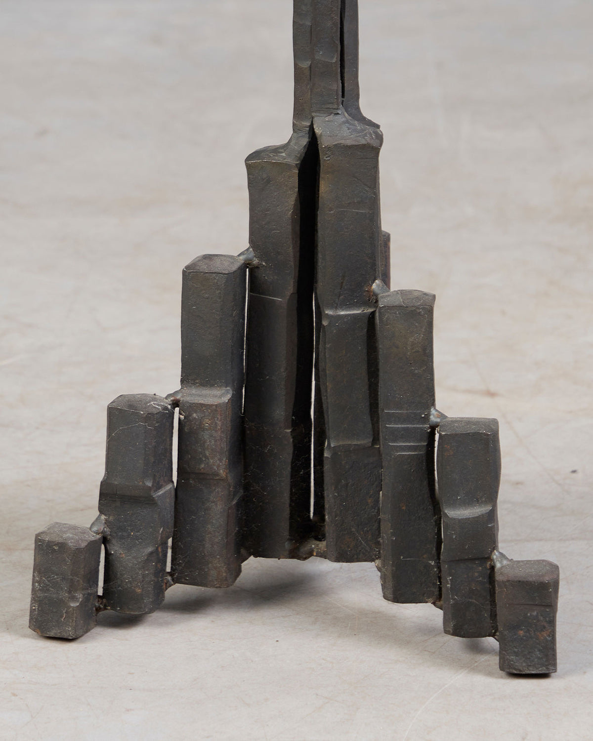 Brutalist iron candle stand base detail showing geometric legs