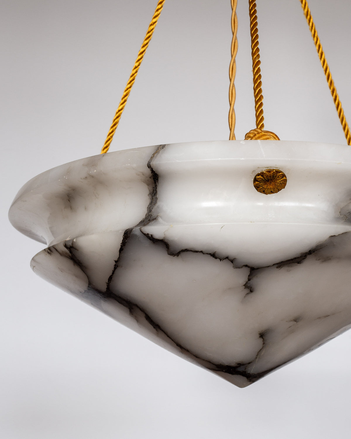 A close-up shows the Spigel Art Deco Diamond Alabaster Pendant, a marble-patterned hanging light with gold accents and twisted gold cords, ideal as statement lighting against a plain, light background.