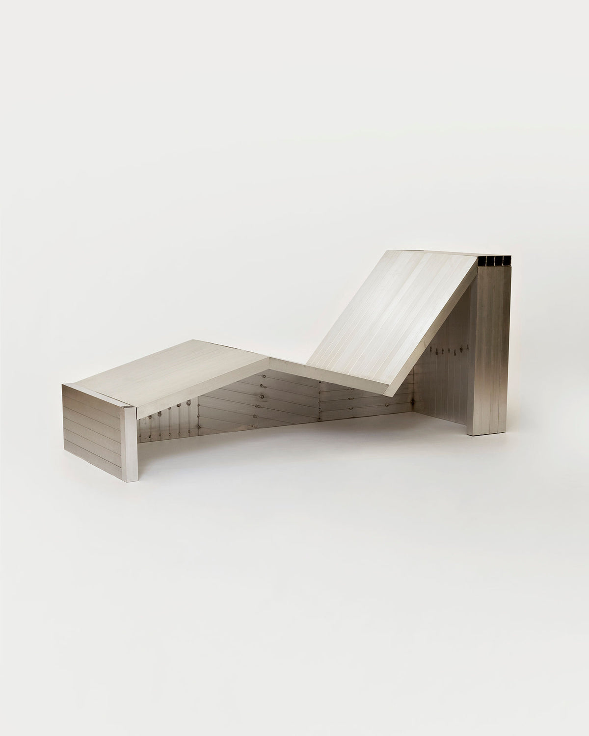 The Aluminum Lounge Chair by Studio HAOS showcases sharp, geometric lines and a minimalist metallic aluminum tube design, exemplifying modern style against a clean white background.