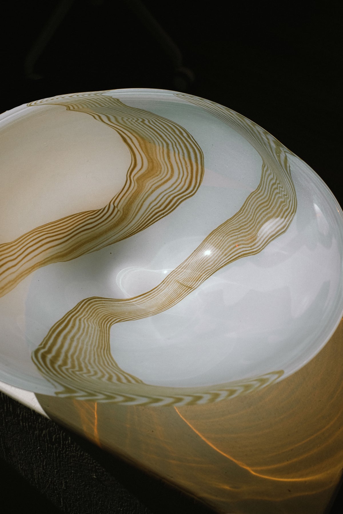 Large blown glass bowl with flowing amber striations on white base