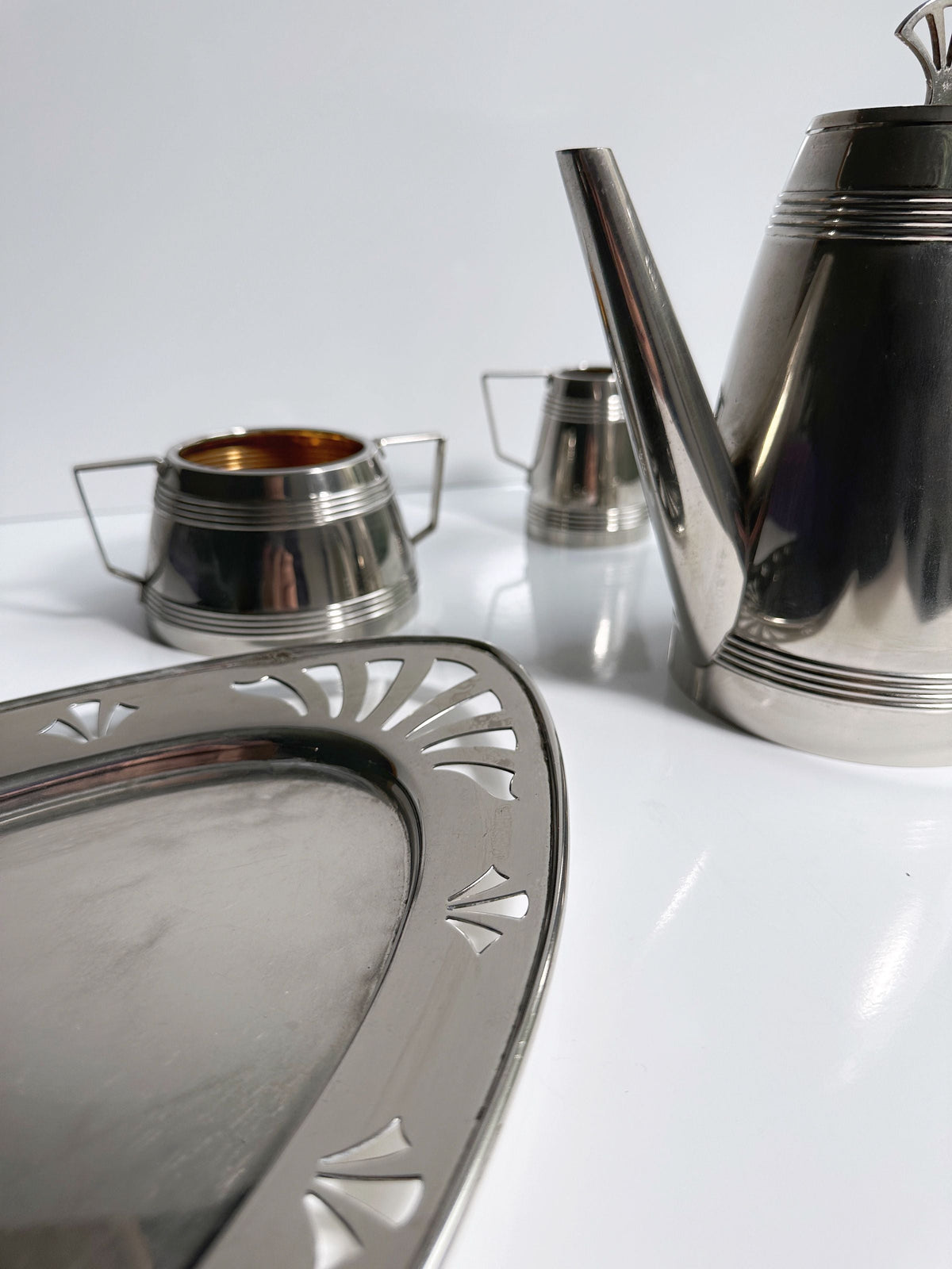A close-up of the Dodo Vintage 1930s Art Deco Silver Coffee Set, featuring a tray, teapot, sugar bowl, and creamer with polished hotel silver plating on a white surface.