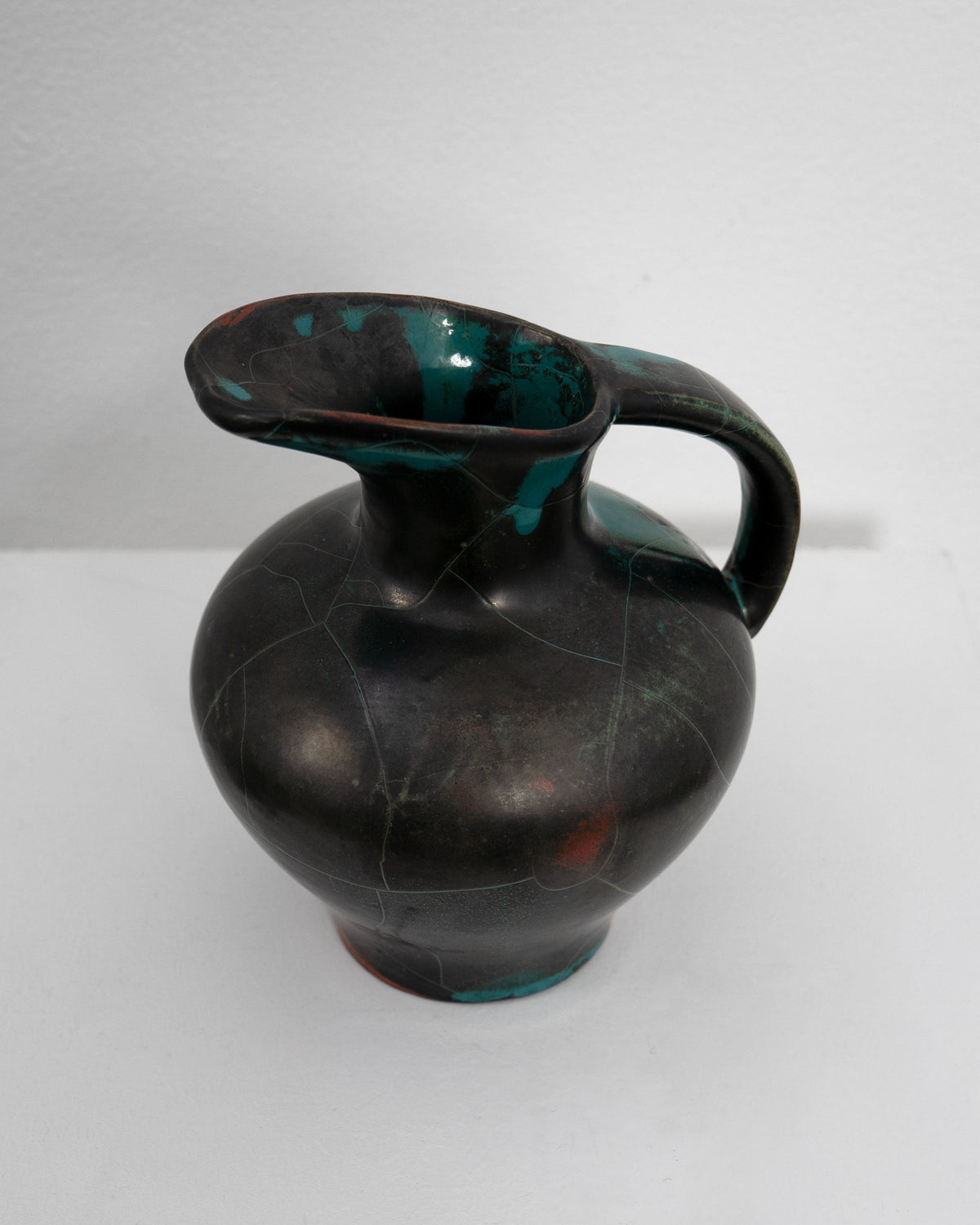 Glazed ceramic jug with dark body and teal accents by Uhlemeyer