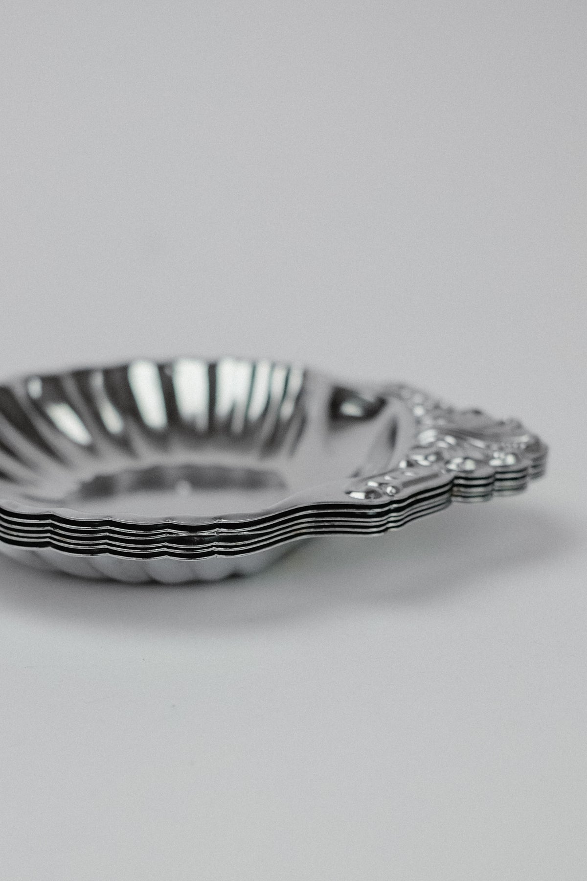 The image displays a shell-shaped dish from the "Set of 6 Small Shell Dishes" by septembre studios. Photographed at an angle against a white background, the reflective surface and ornate handle highlight its polished, metallic finish and unique vintage charm.