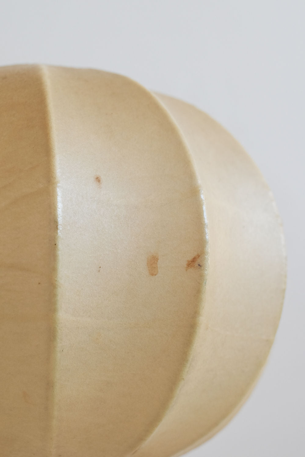 Curved ceramic detail of Cocoon table lamp showing warm beige finish
