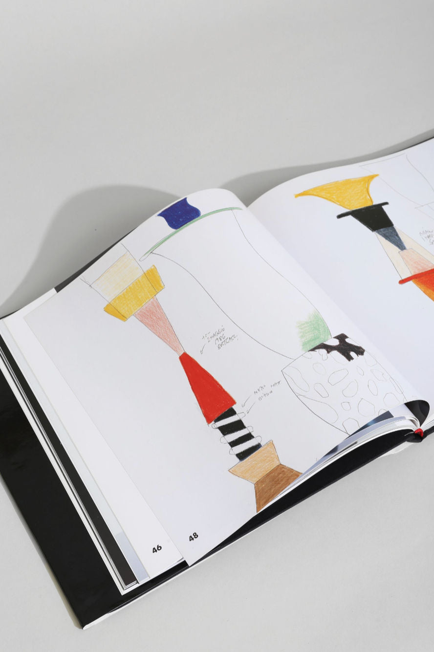 The Villa Ettore Sottsass, Glass Works Book is open to pages 44–45, displaying abstract, colorful, hand-drawn shapes and geometric patterns inspired by Sottsass on white pages.