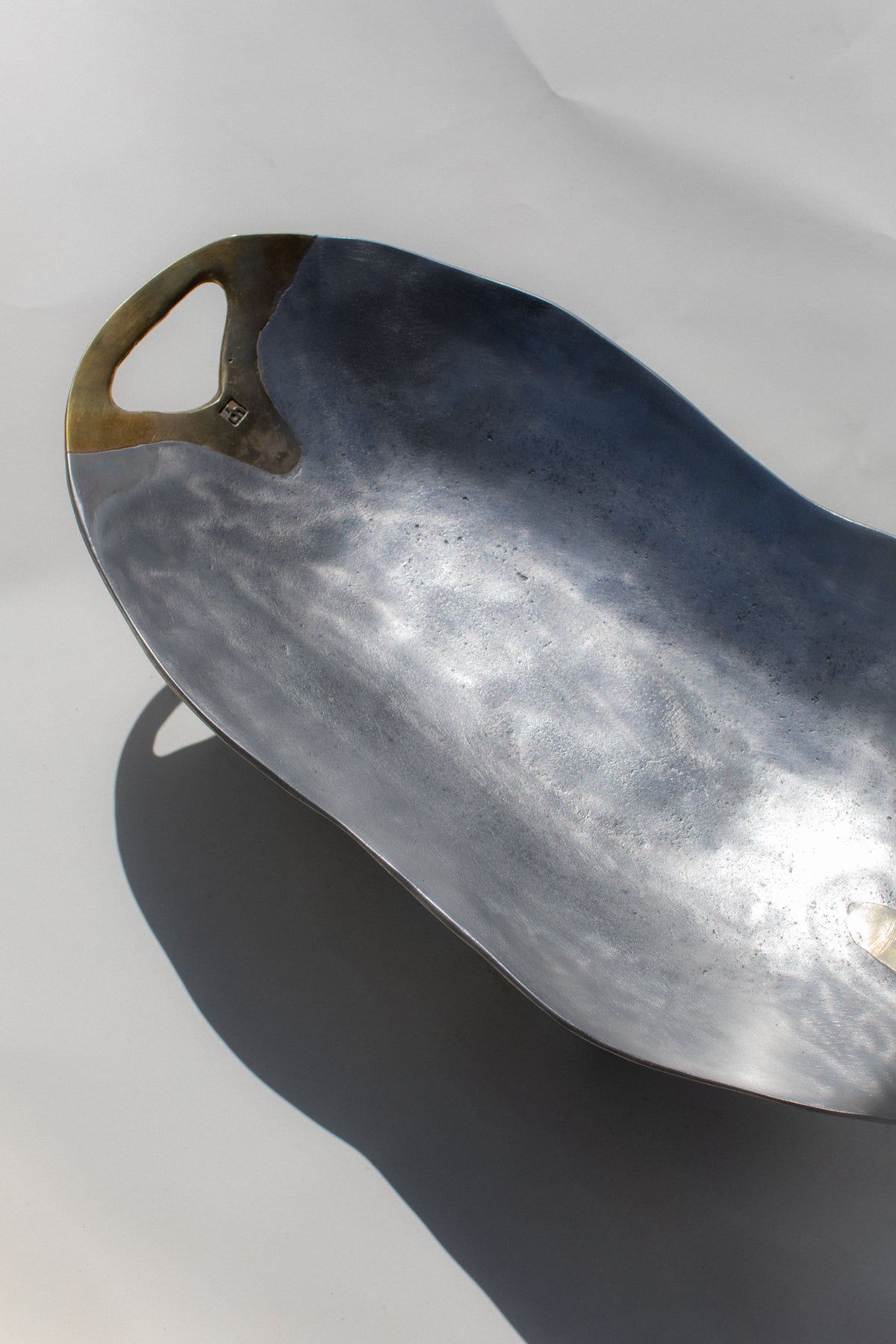 Brutalist metal bowl with curved handle showing patina finish