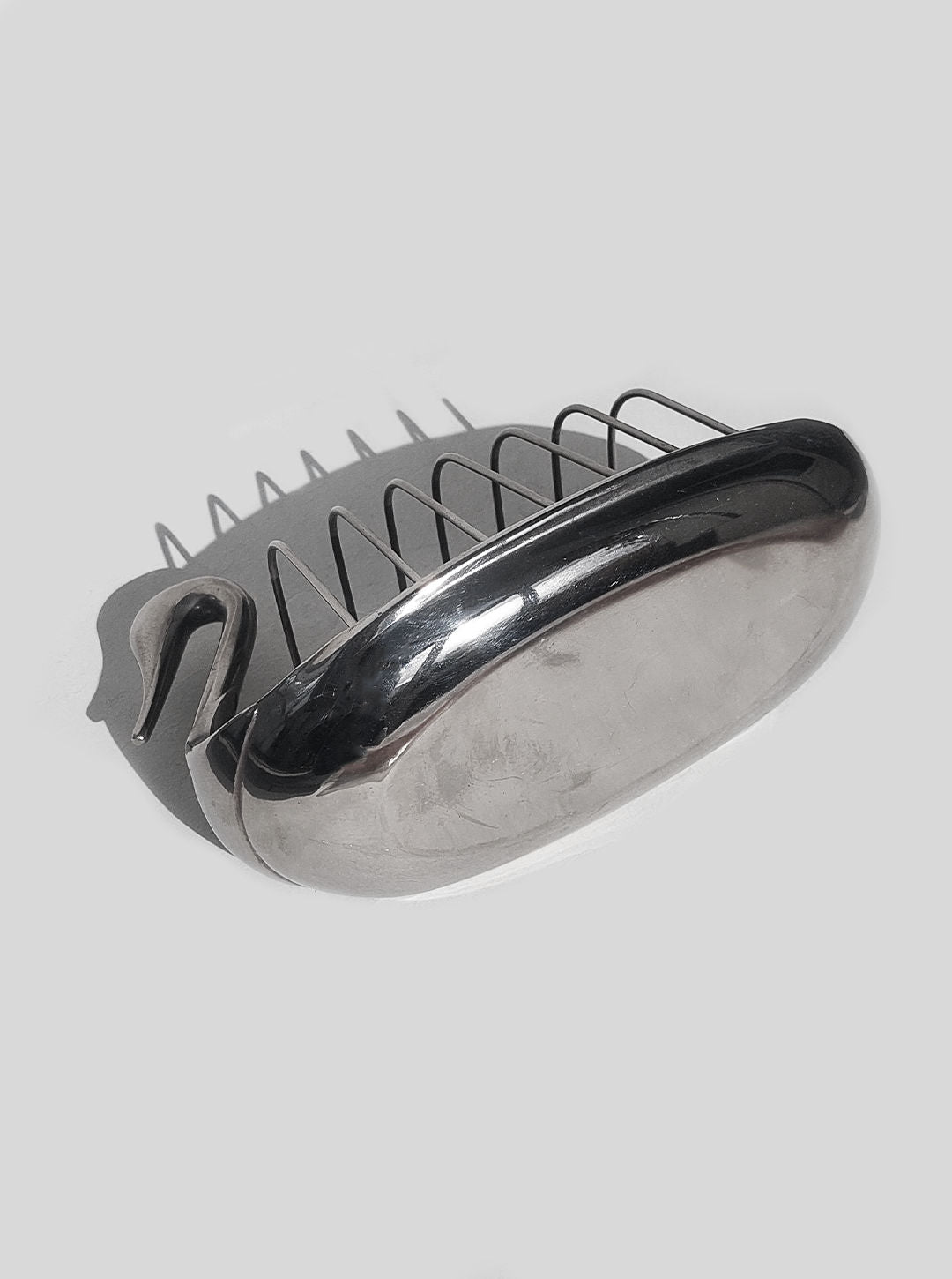 A brass Les Objoies swan toast rack with a soap holder featuring closely-spaced, spring-like steel wires, against a plain white background.