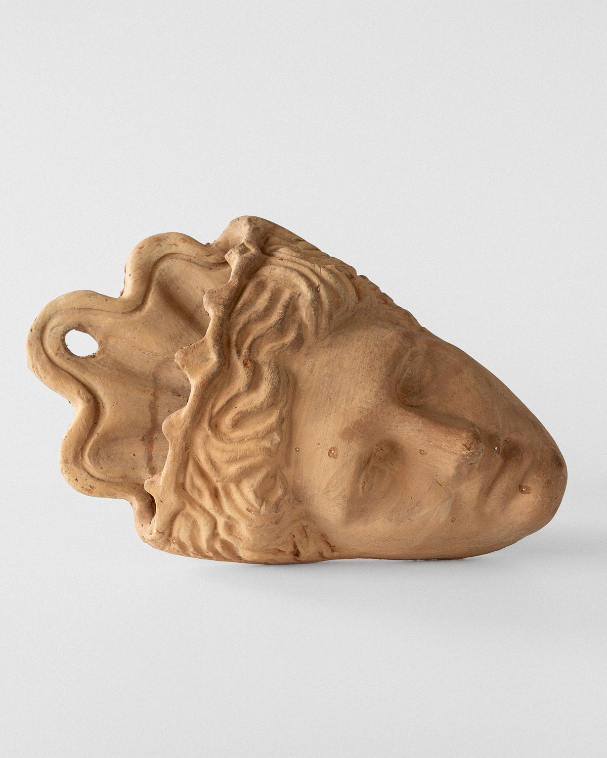 The Spigel Terracotta Wall Mask Planter features a classical-style face with wavy hair and a serene expression. Designed for easy hanging, it lies flat with a side profile visible, set against a plain white background.