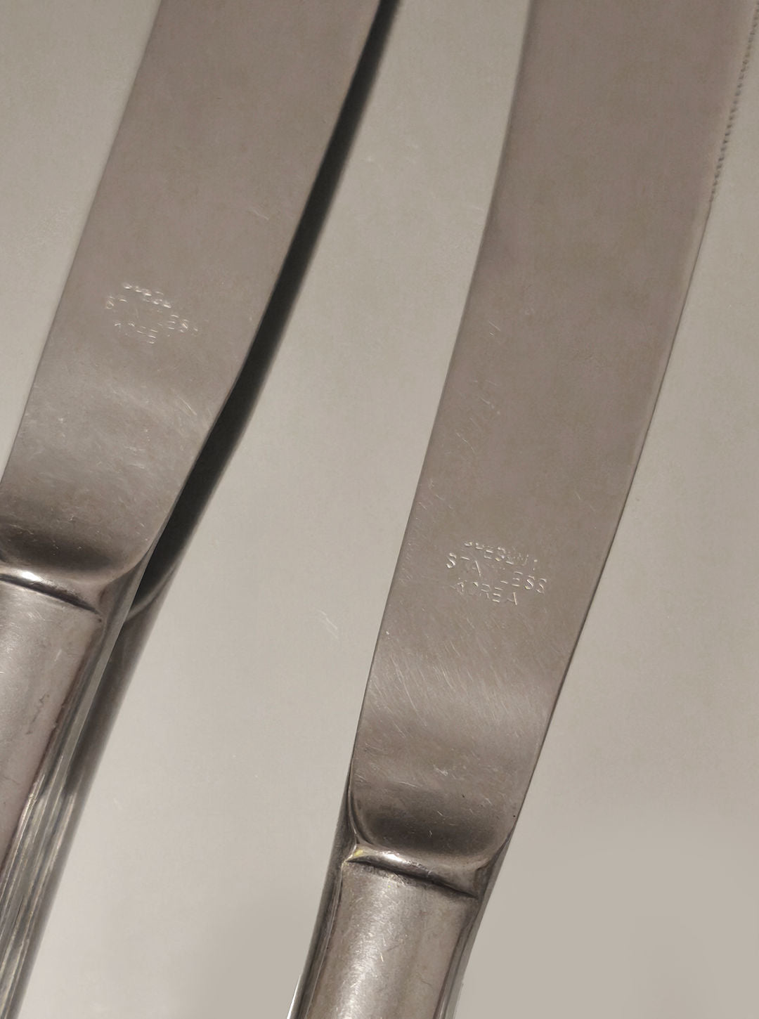 Close-up detail of stainless steel butter knife blades with engraved markings