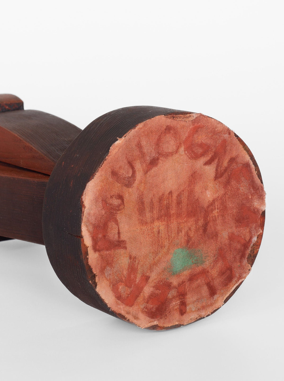A close-up of the Cubist Sculpture mallet by Spigel, featuring a dark wooden handle and a faded, worn fabric covering on one end. The fabric is marked with indistinguishable red text, where 'BOULOGN' can be seen faintly at the atelier Boulogne label. The material appears frayed and slightly discolored with a small green spot near the bottom center.