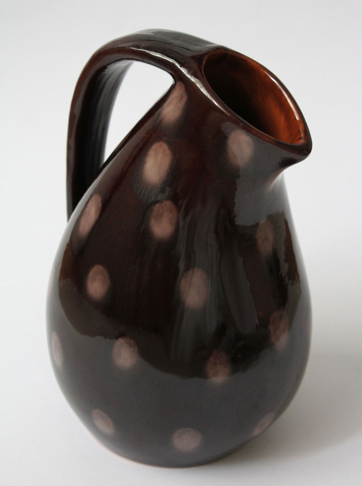 Brown ceramic dotted jug with curved handle - side profile view