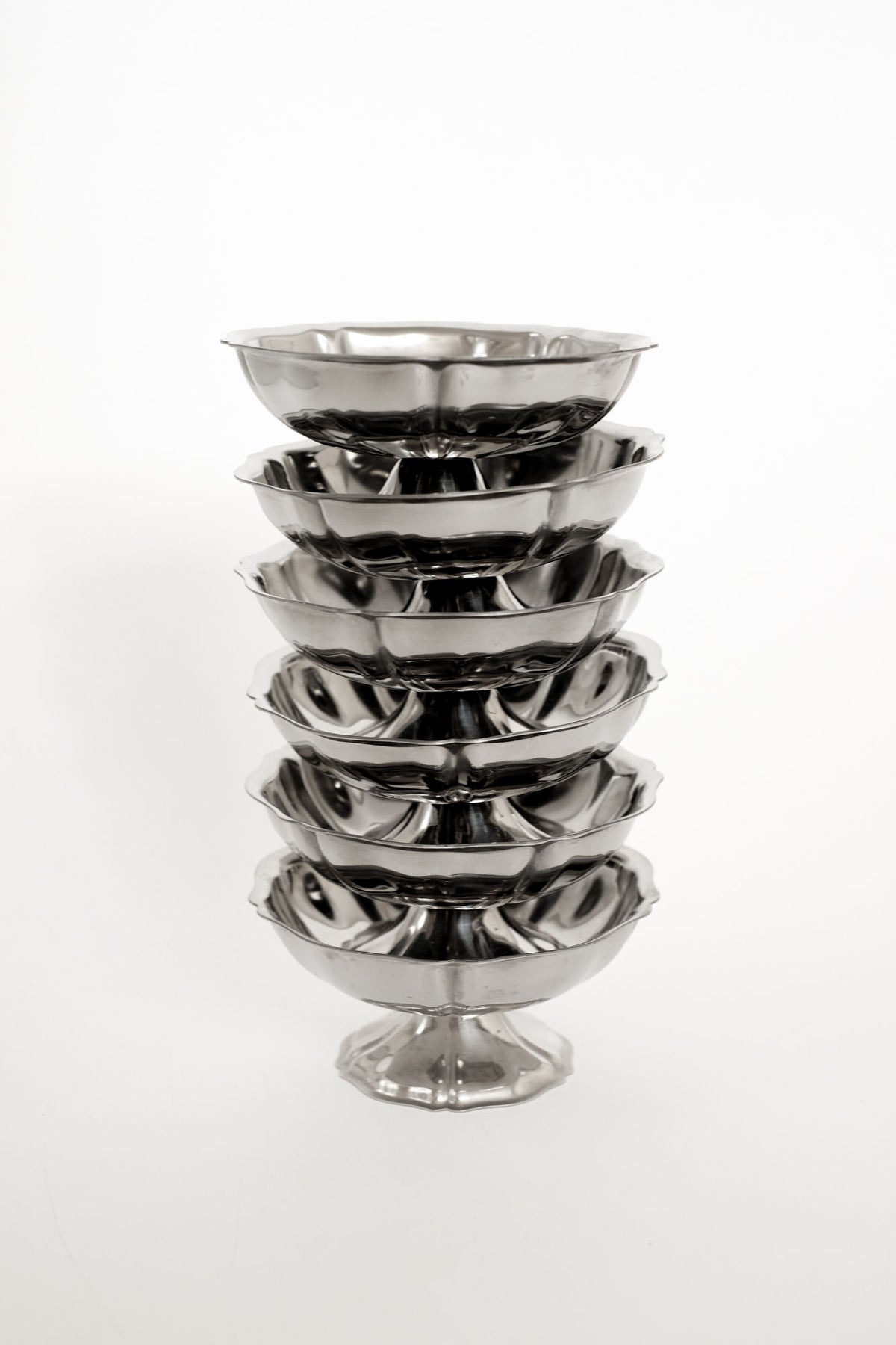Stacked Guy Degrenne polished steel ice cream bowls with pedestal base