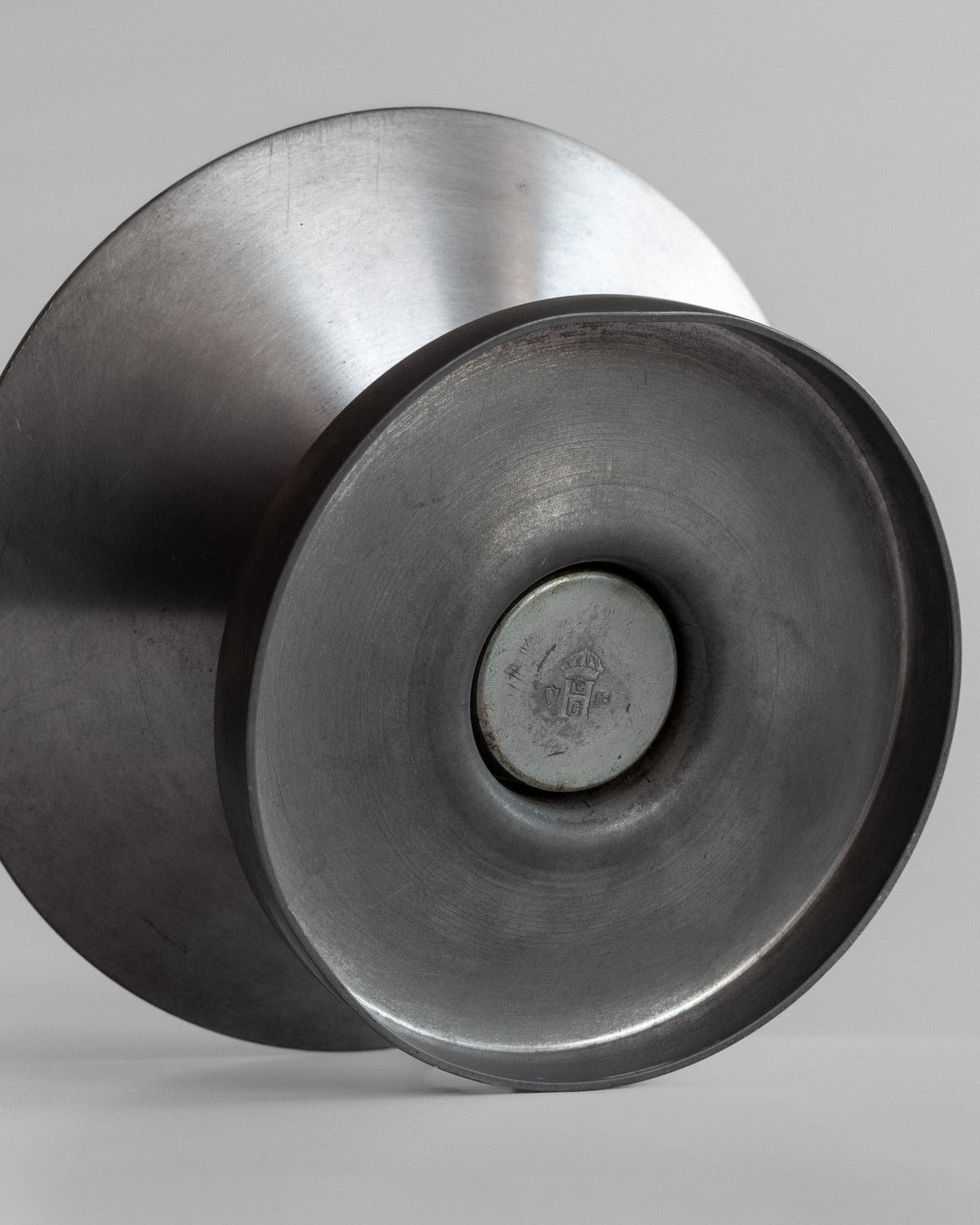 The close-up shows two reflective, concentric metal discs resembling modernist artwork. These discs are slightly angled and highlight their shiny texture, part of the Modernist Candleholders by Sylvia Stave from the 1930s, under the Spigel brand.
