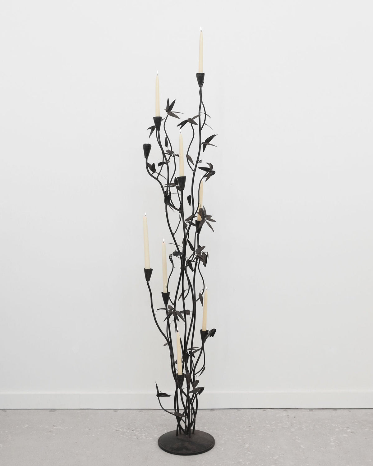 Tall black iron candelabra sculpture with branching stems and leaves