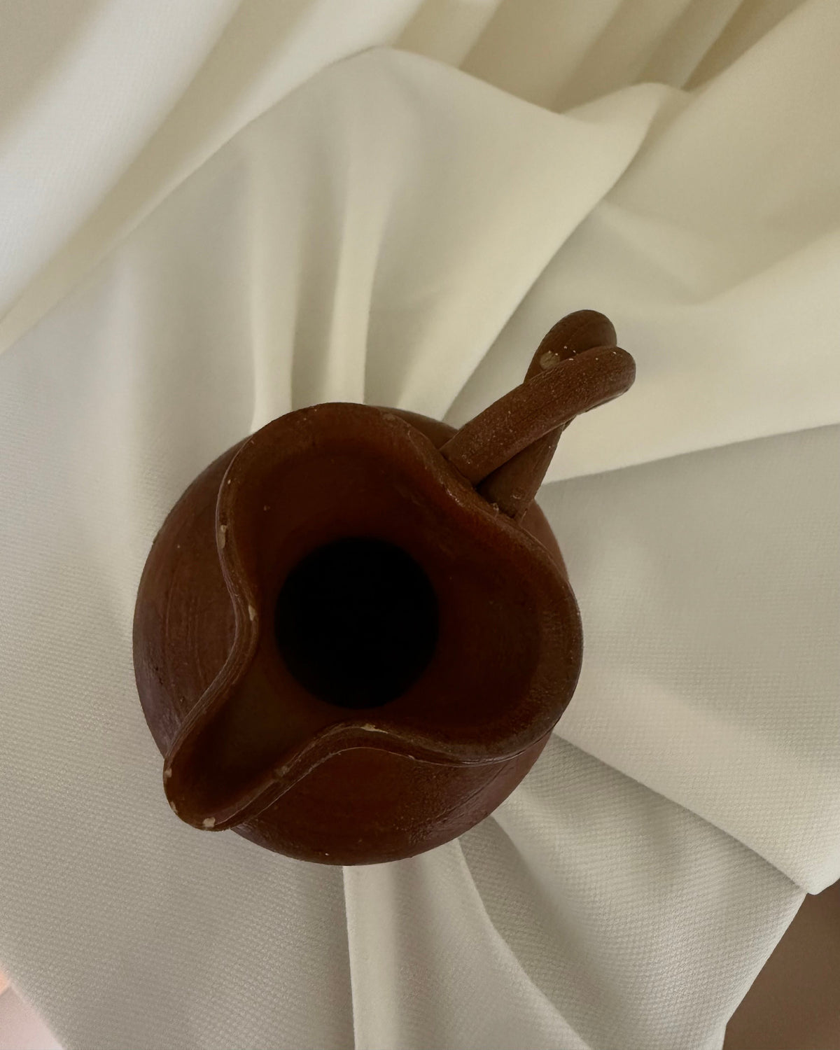 Interior view of small handcrafted ceramic pitcher showing spout