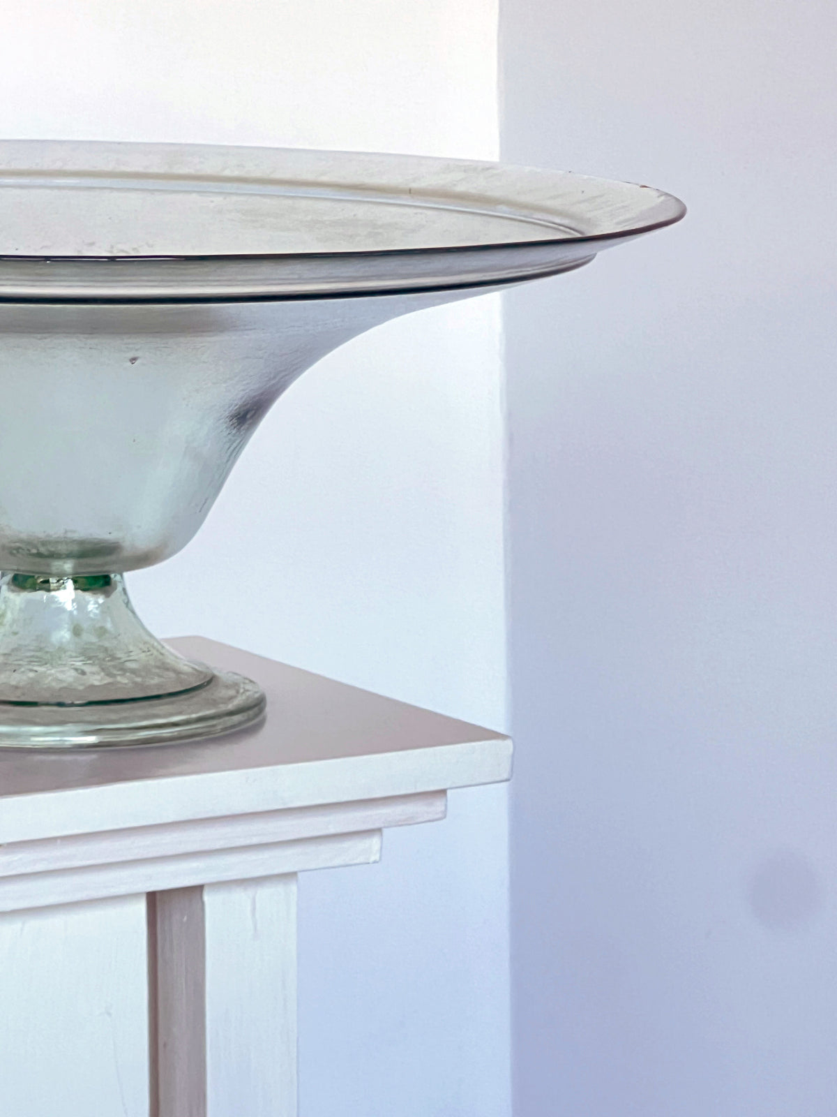 Clear glass pedestal dish with curved bowl on white surface