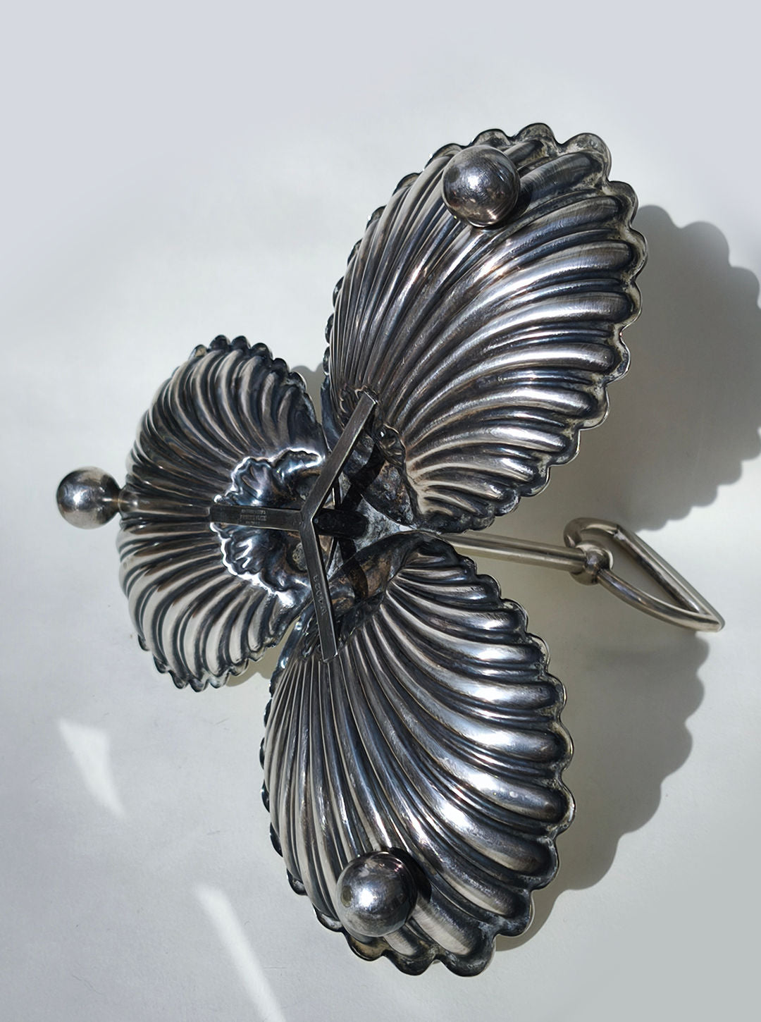 The Les Objoies Large Silver-plated Triple Tray features two shell-shaped compartments joined by decorative ridges, metal spheres on each end, and a back handle, adding elegance to any table setting.
