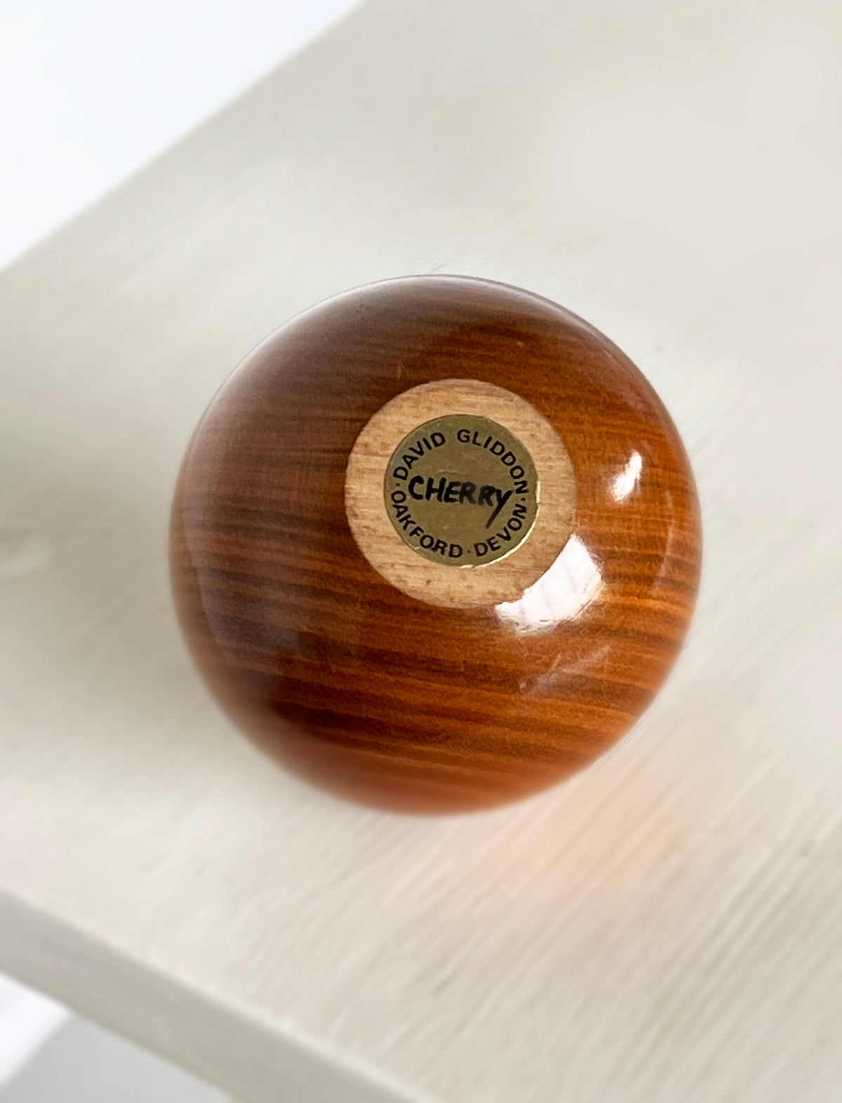 Polished cherry wood sculpture bottom view showing maker's stamp
