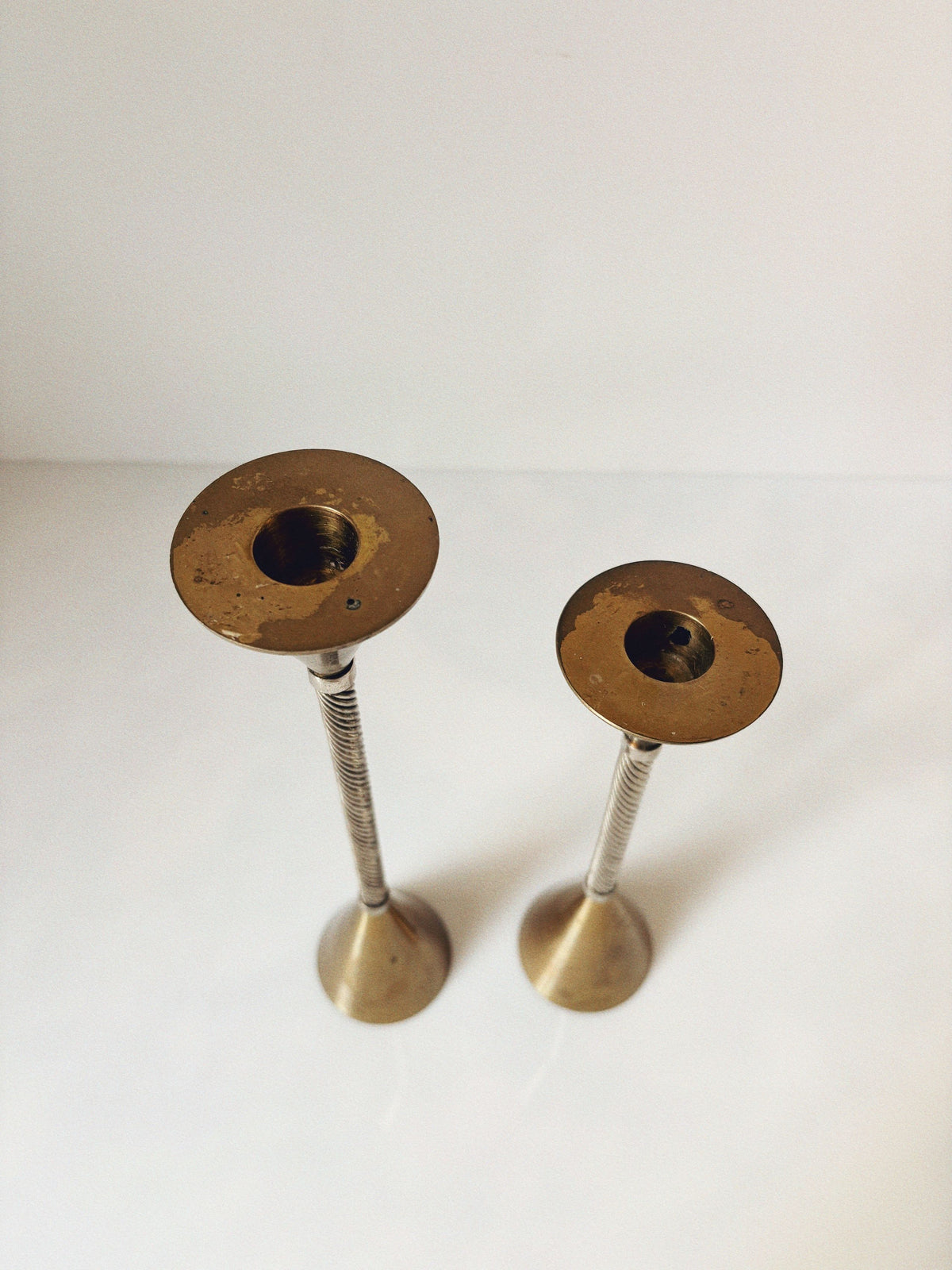 Brass candleholders with threaded stems showing tarnished patina