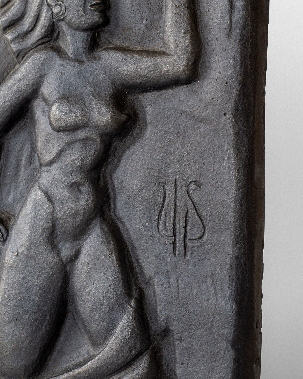 Detail of cast iron wall relief showing carved figure with trident symbol