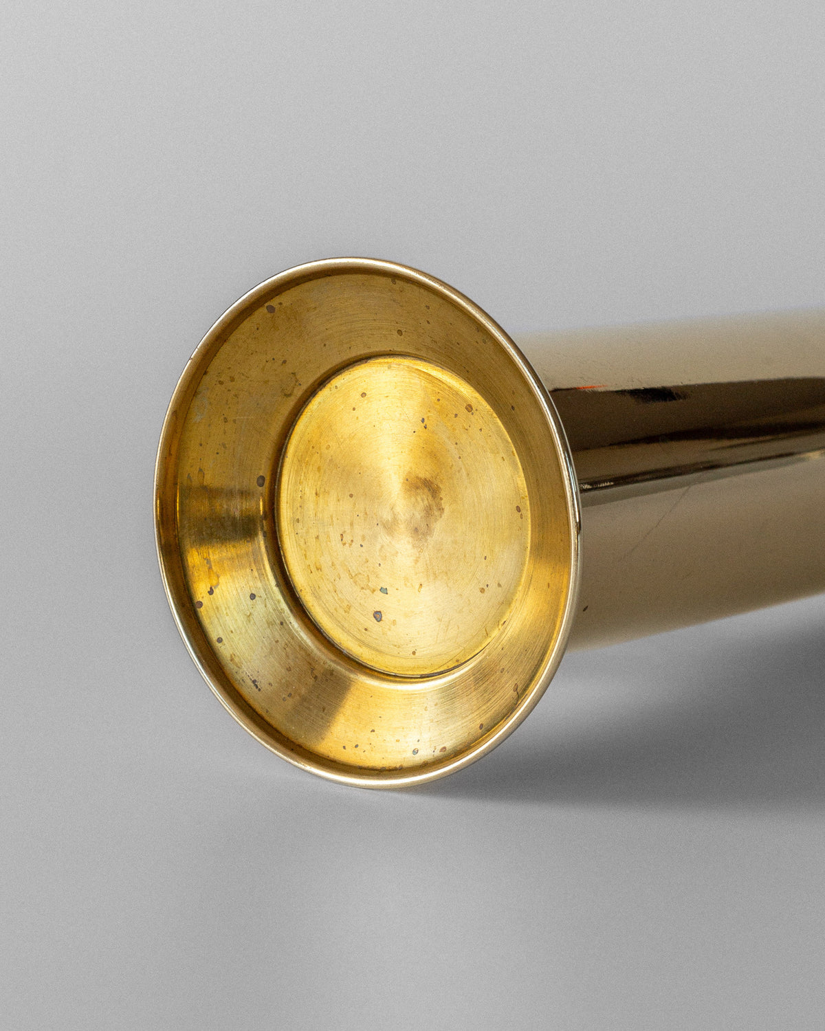 A close-up of the Large Mid-Century Brass Vase by Spigel, its glossy finish and sculptural bell-shaped form evoke Scandinavian modernism against a plain light gray background.