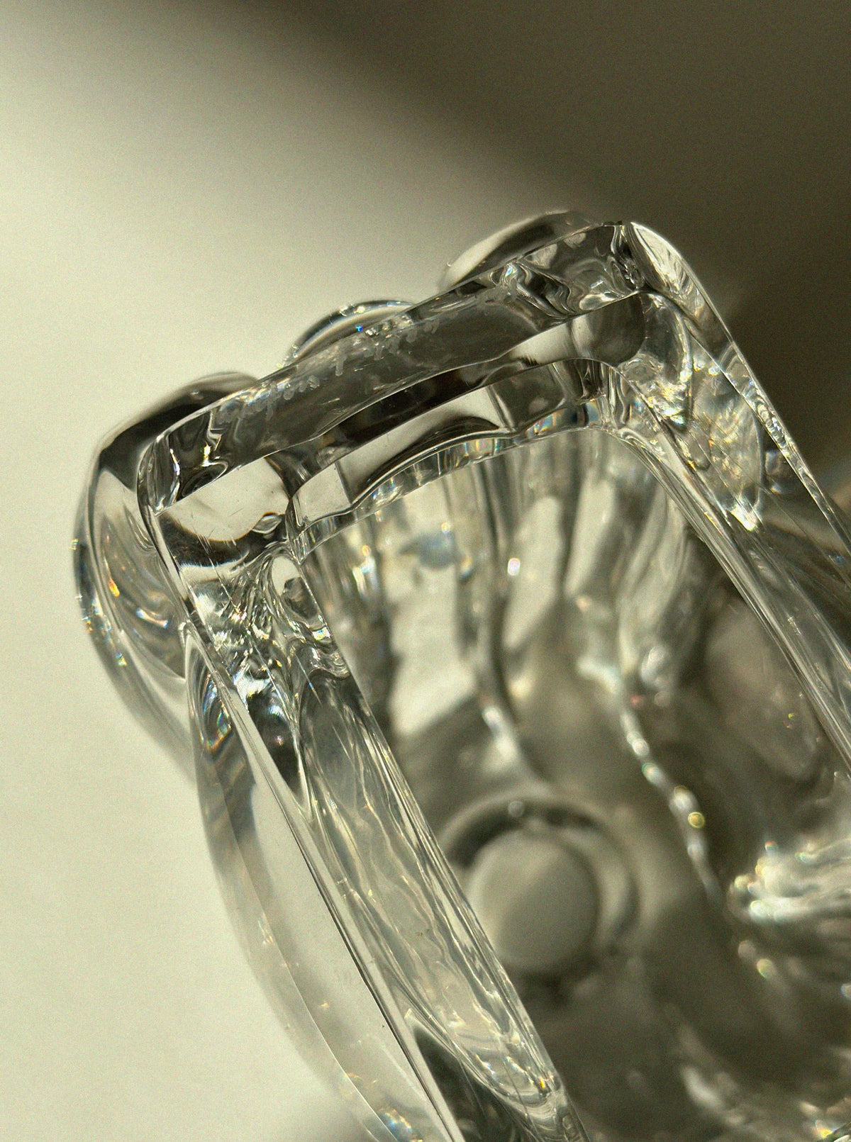 Close-up of a Lars Hellsten "Tulip" Crystal Glass Vase by Vintage Stories, featuring smooth, curved surfaces that reflect light and cast subtle shadows on a white background.