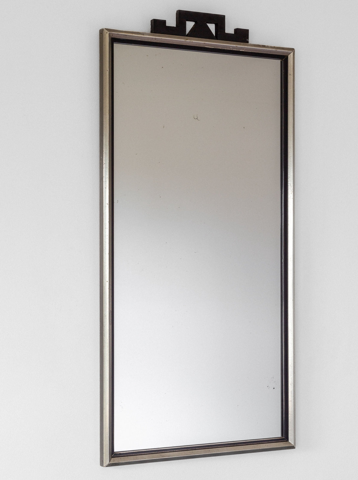 Mounted on a white wall and reflecting part of the surrounding room, the Swedish Art Deco Mirror from Spigel features a vintage 1930s wooden frame with a small decorative black element at the top. This mirror combines simplicity with modern elegance, enhanced by an Art Deco twist.