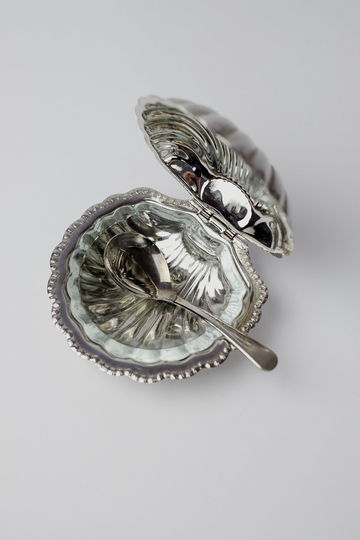 The Shell Shaped Butter Dish with Spoon by septembre studios, intricately designed in vintage brass resembling an open seashell, includes a matching spoon. This elegant piece elevates any dining experience and is showcased on a smooth, white background.