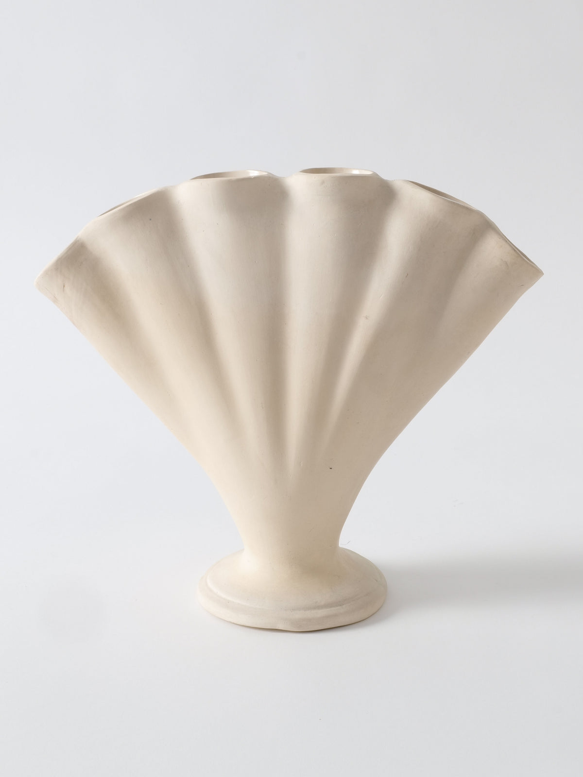 A photo of the Tulipiere Vase 1930s designed in the shape of a fan. The vase, from Collection apart, is beige and features a fluted, scallop-like pattern with a rounded base, accentuating its fan-like appearance. The background is plain white.