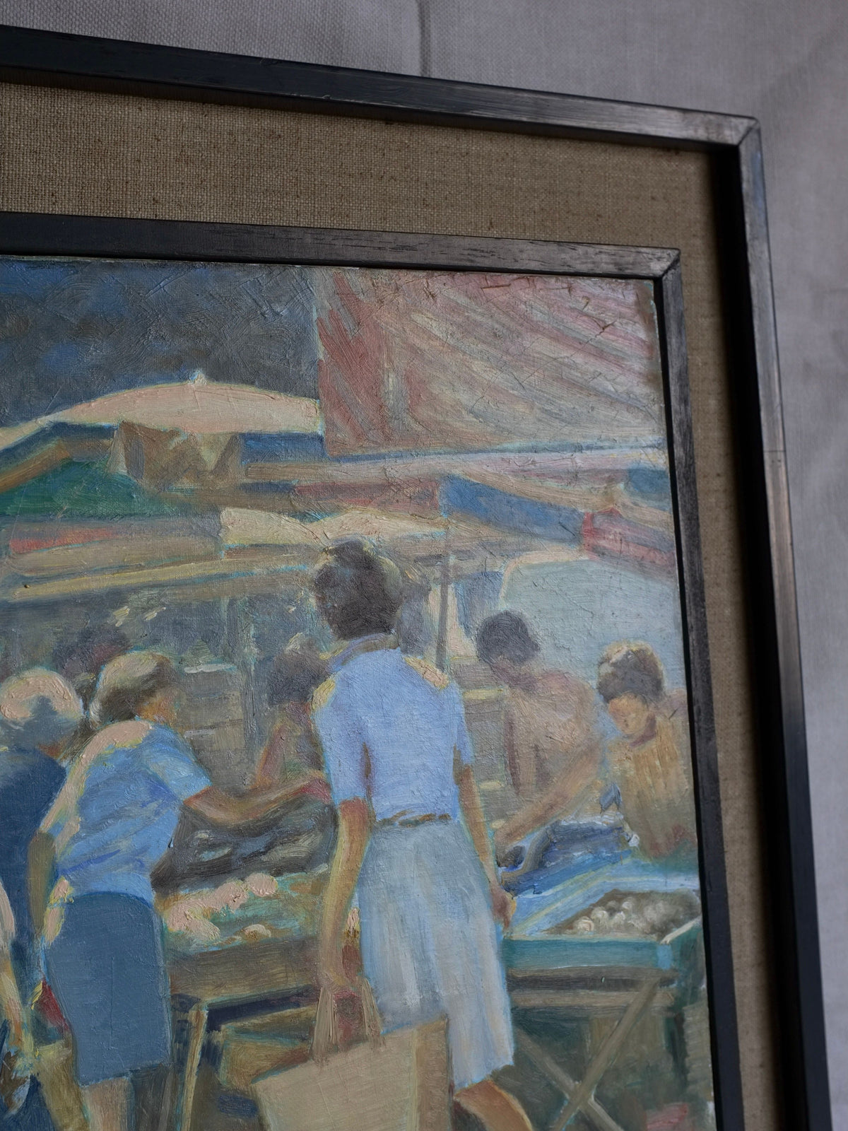 A framed painting titled "Vintage Genre Oil Painting with Market Scenes" by Veter Vintage. It depicts a summer market day with several people gathering around a stall, possibly buying or selling items. The background shows various awnings and market structures with soft colors predominating in blues, tans, and greens—a delightful vintage oil painting by a Spanish artist.