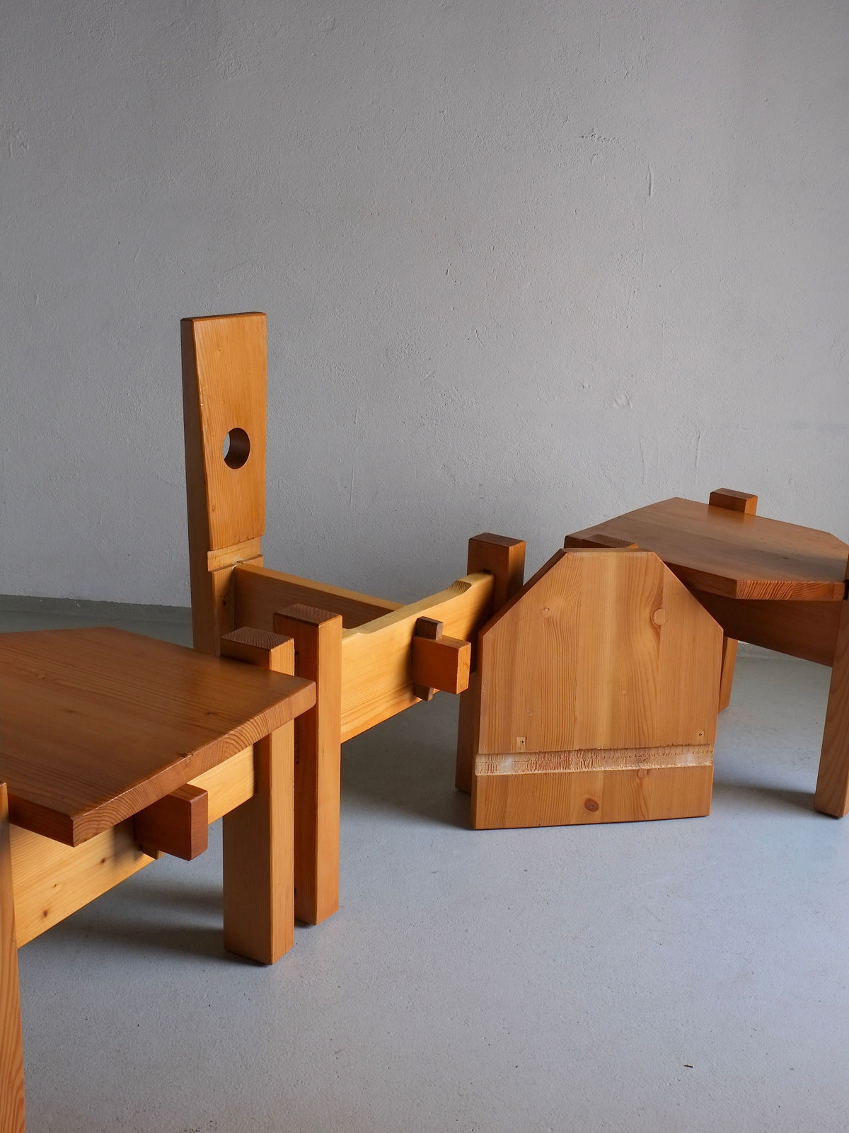 This sculptural pine chair, designed by Erwin Egel in the 1960s and offered by Veter Vintage, features a modular design with rectangular parts and a circular cutout on the backrest. It is partially disassembled against a plain, light-colored wall.