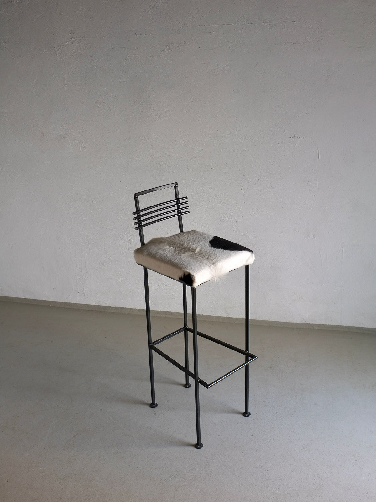 Vintage wrought iron bar stool with cowhide seat detail view